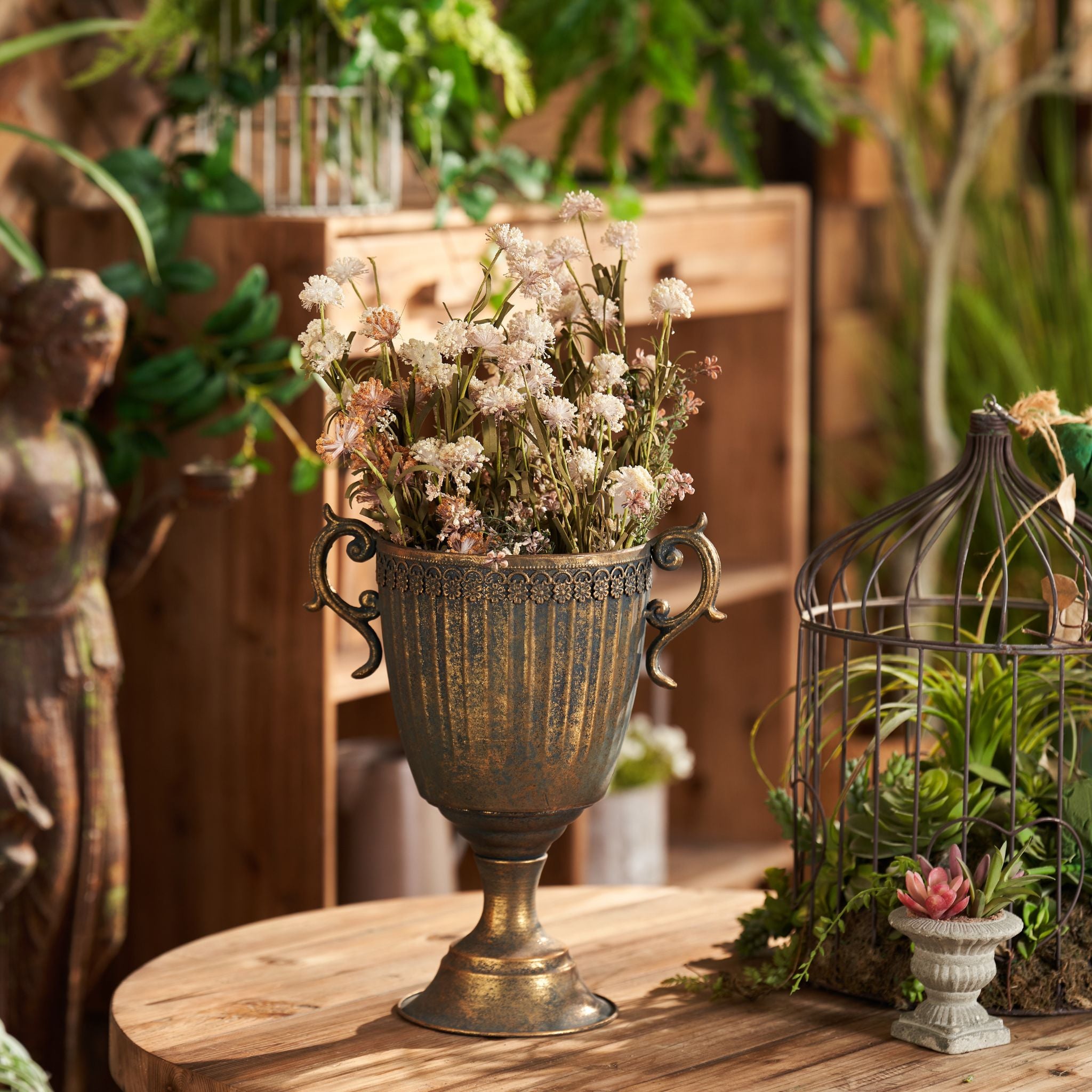 Olympia trophy urn in bronze style finish with dried wildflowers on a garden table