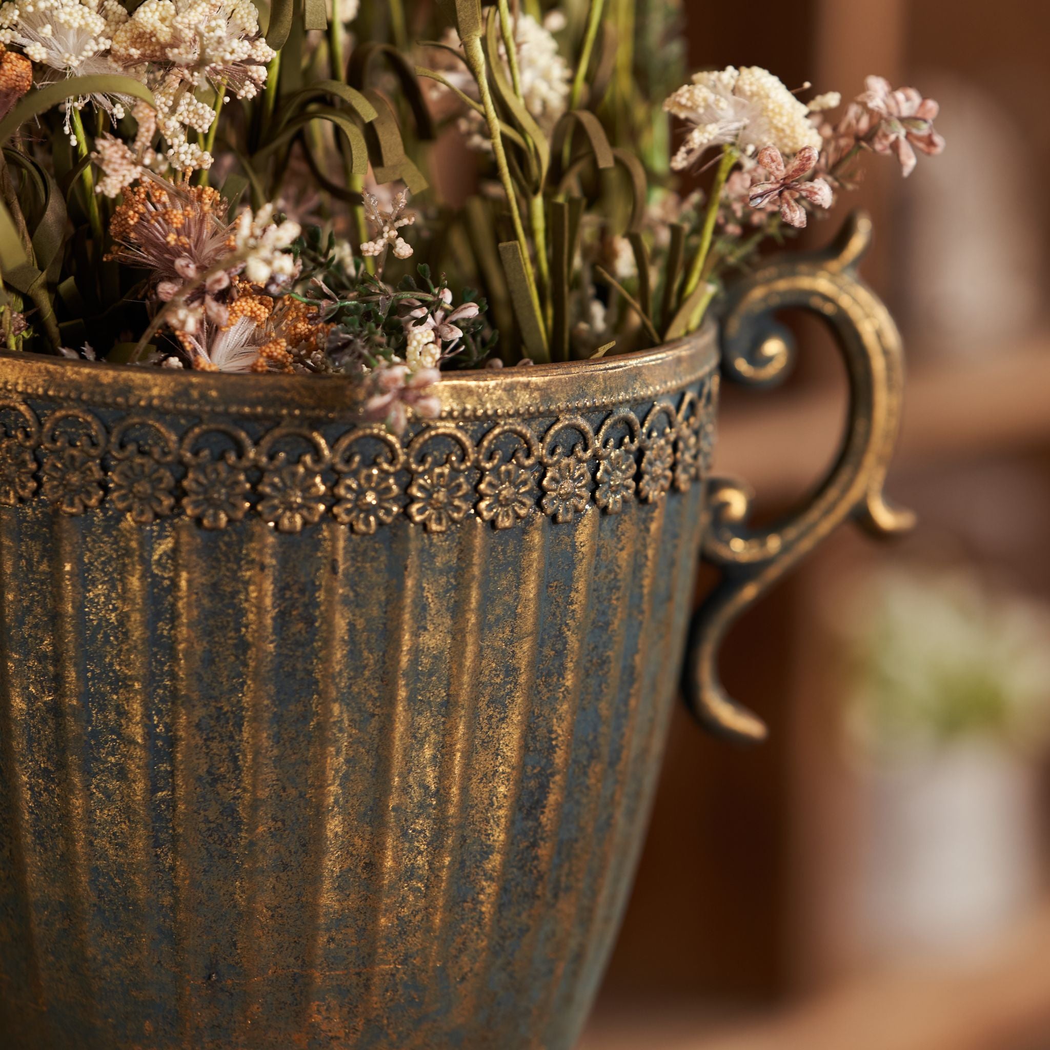 Olympia bronze style trophy urn with scroll handles styled beside a wire cloche