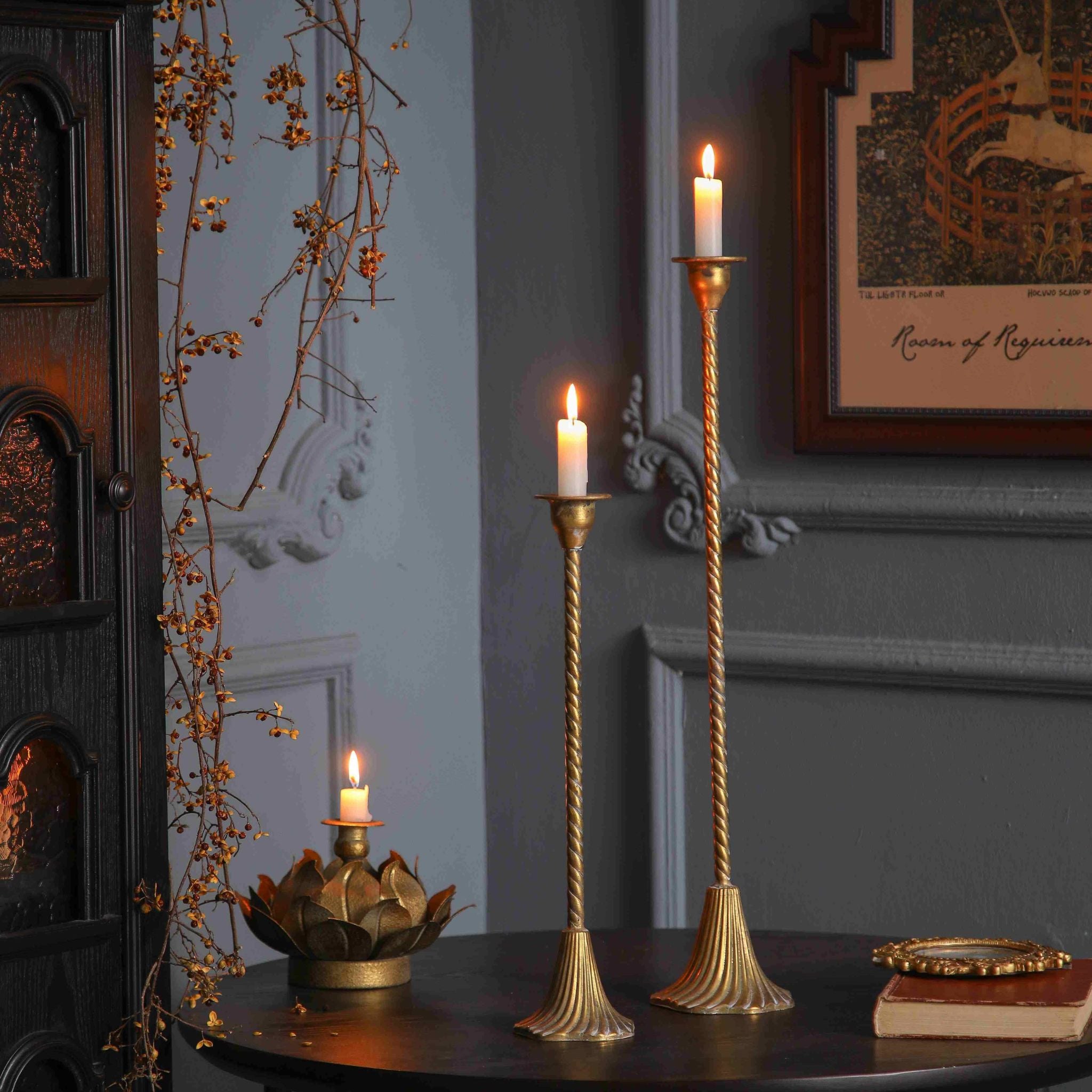 Alma and Amara twisted stem candlesticks in aged gold on a dark table with lit candles