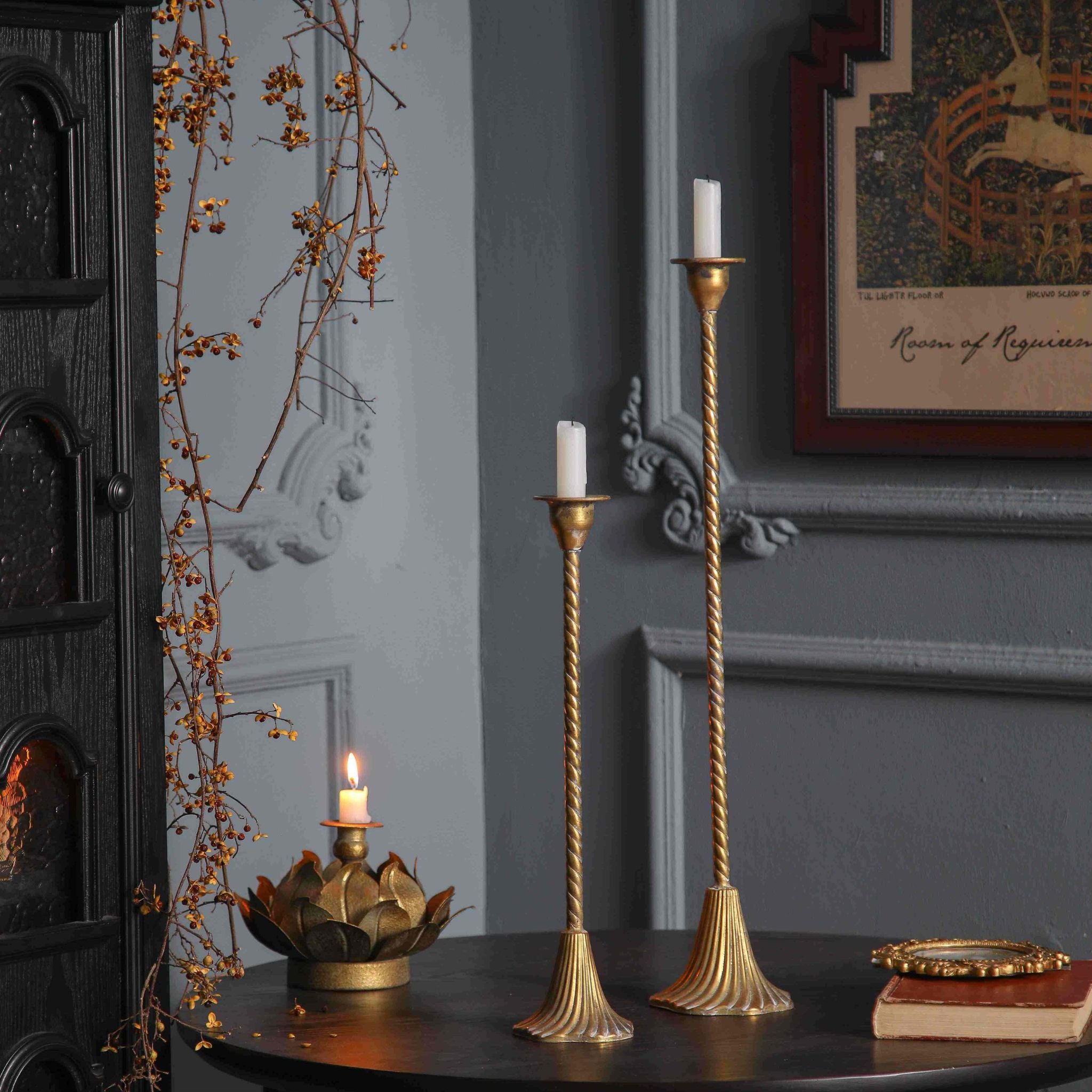 Alma and Amara aged gold candlesticks lit at dusk beside a gold lotus candle holder