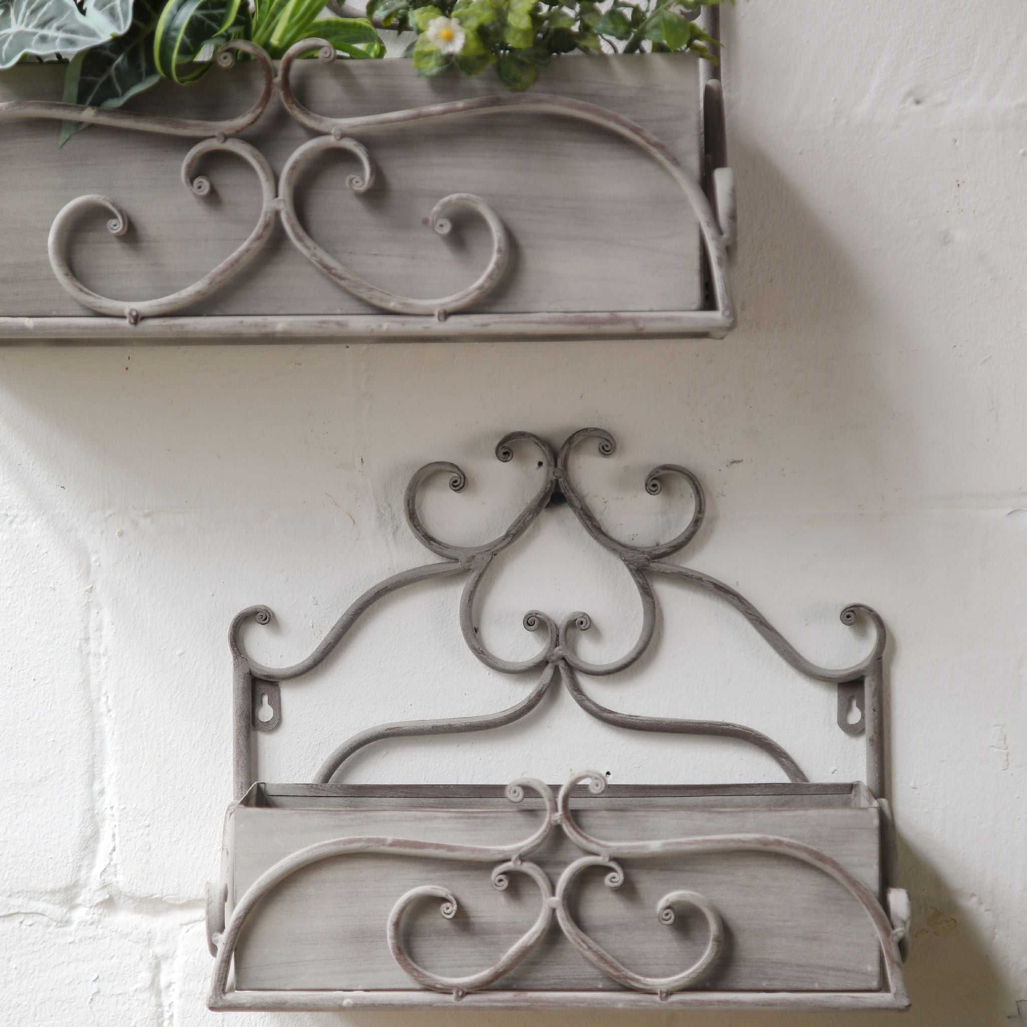 The two Bianca grey iron wall boxes planted with ferns and flowers