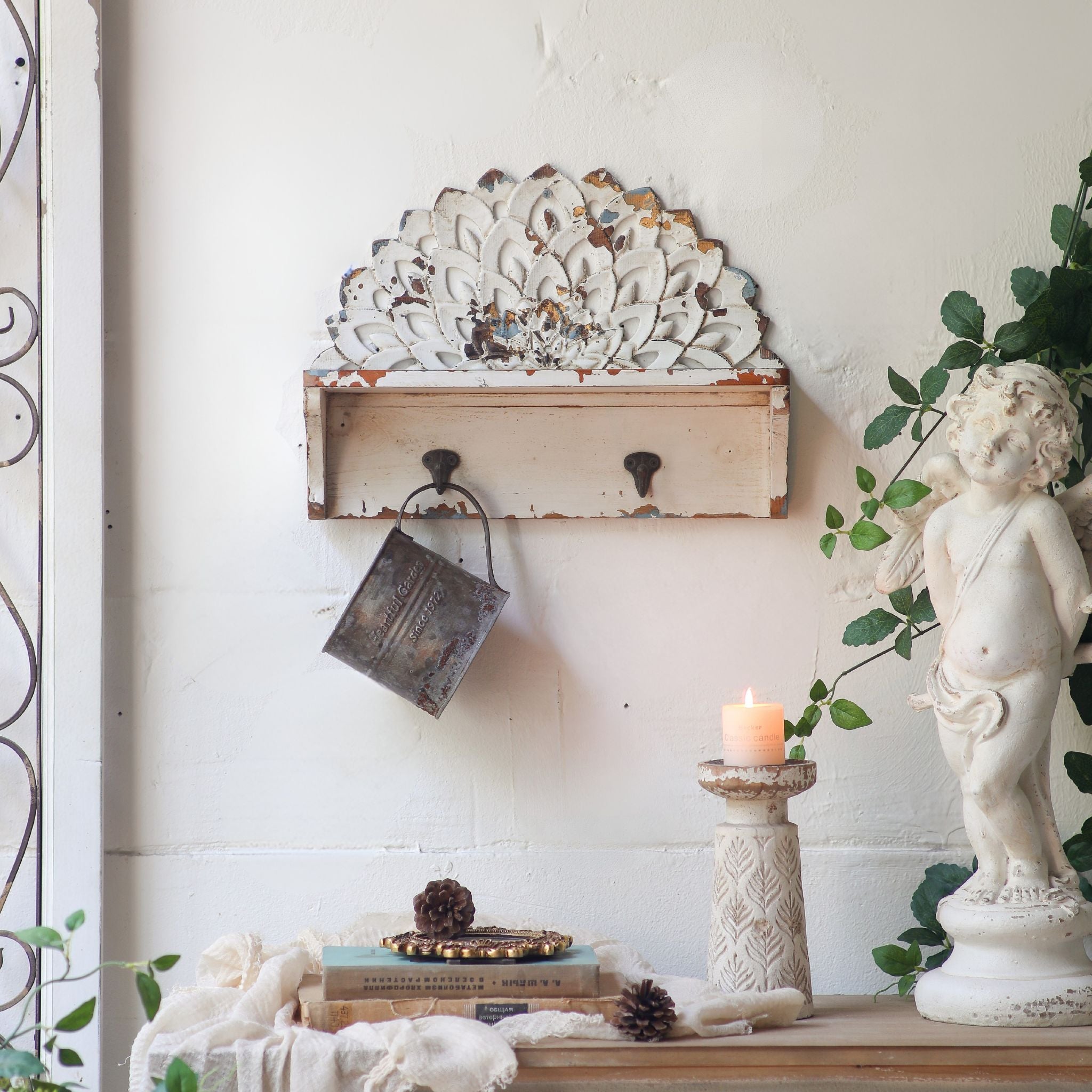 Elio wall shelf with carved petal crest and two hooks in distressed white, angled view