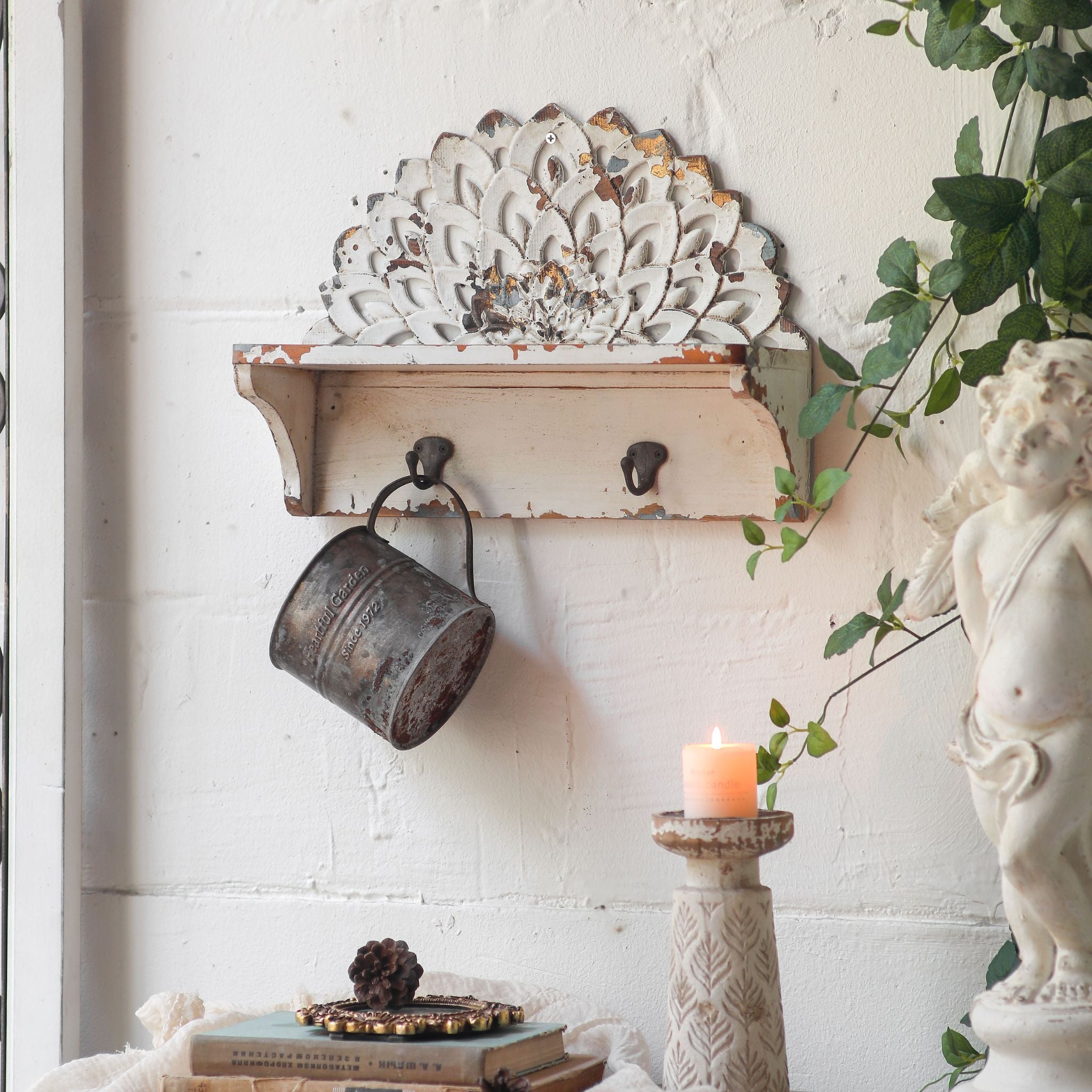 Close view of the carved petal crest on the Elio wall shelf showing chipped white over gold and grey