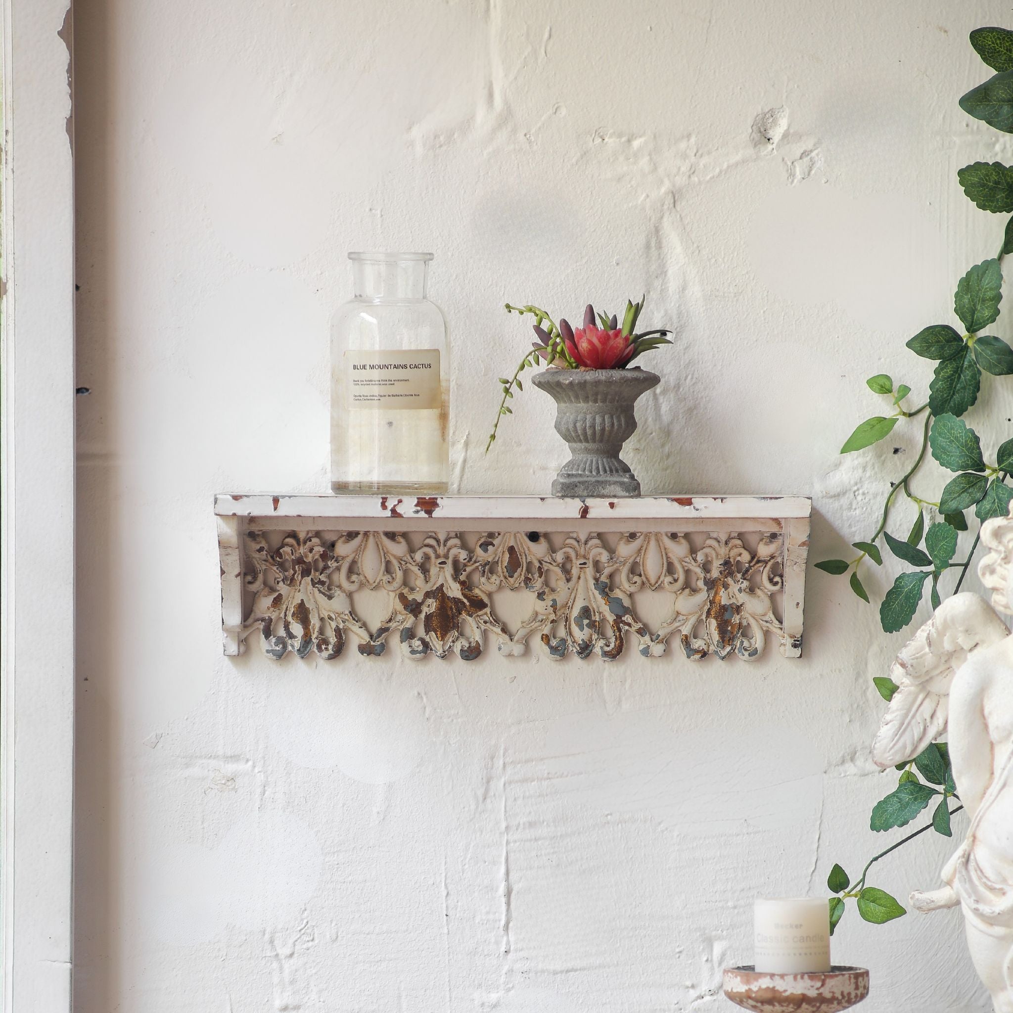 Close view of the carved fretwork apron on the Elias wall shelf in distressed white