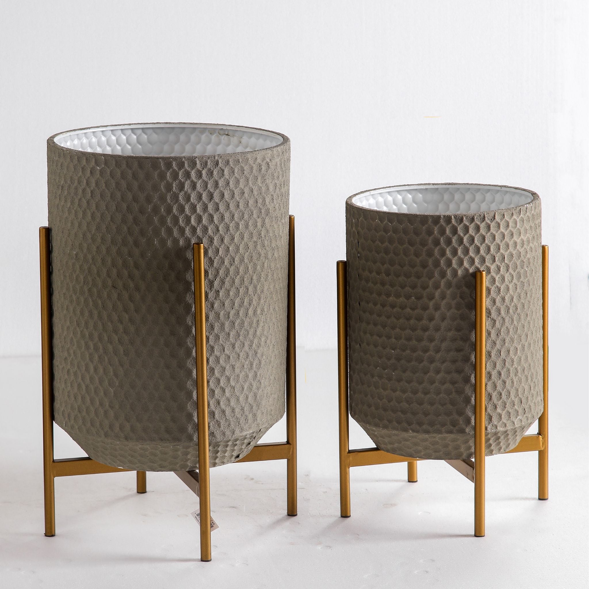 Enzo honeycomb metal planter pair on gold stands, 60cm and 50cm, studio view showing white enamel interiors
