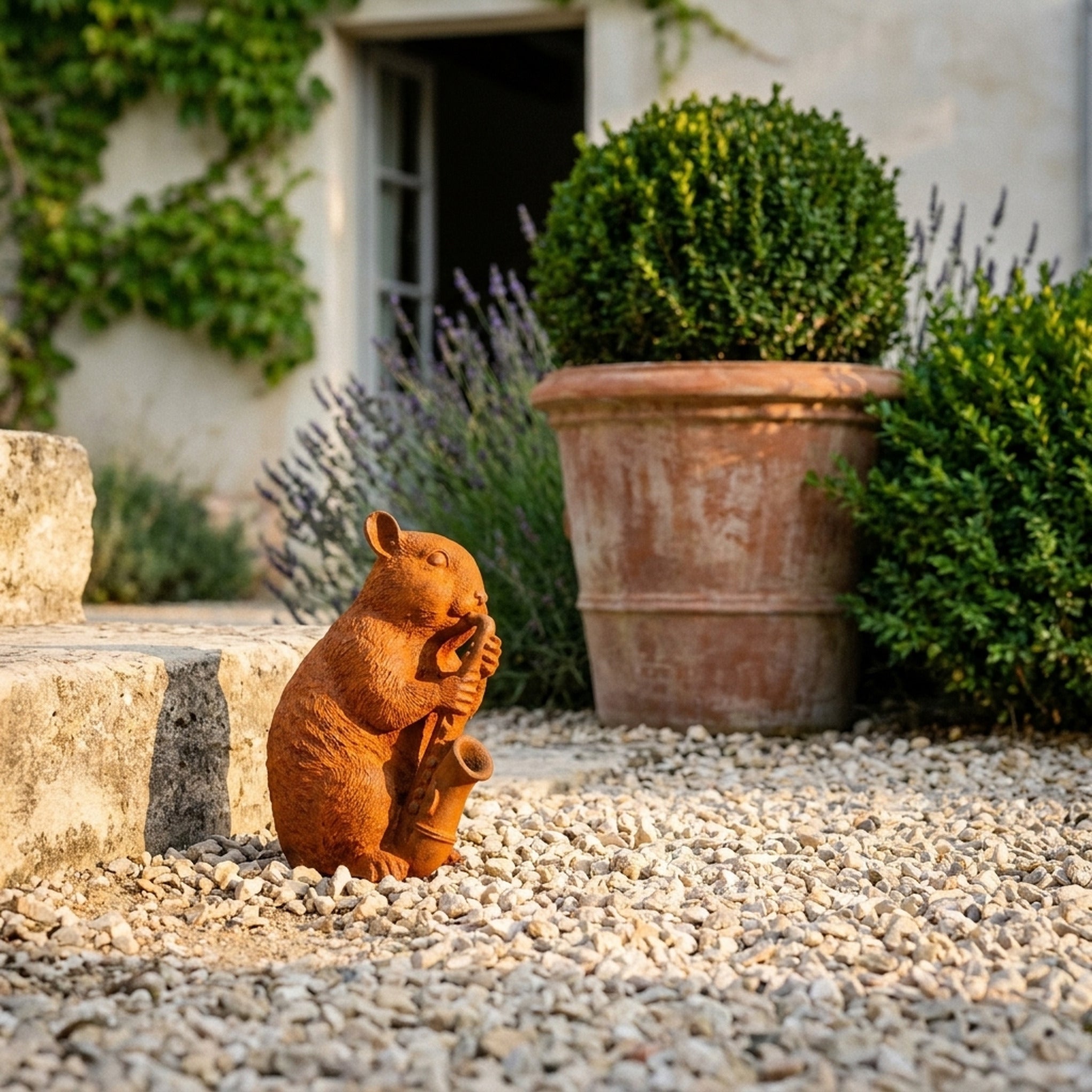 Chester rust cast iron dormouse statue playing a saxophone, on gravel beside a terracotta pot
