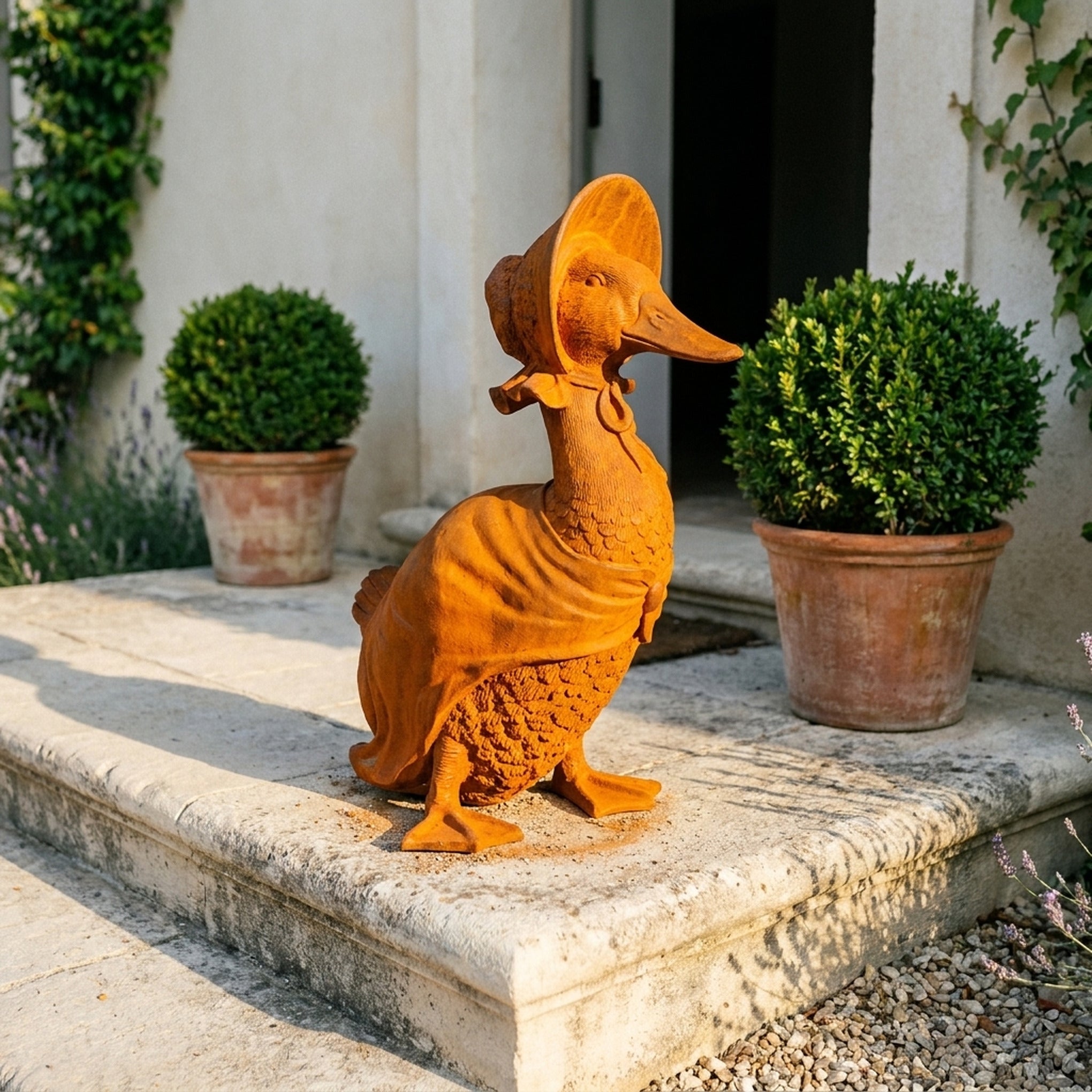 Madame Goosington rust cast iron duck in a bonnet on limestone steps between clipped box in terracotta pots