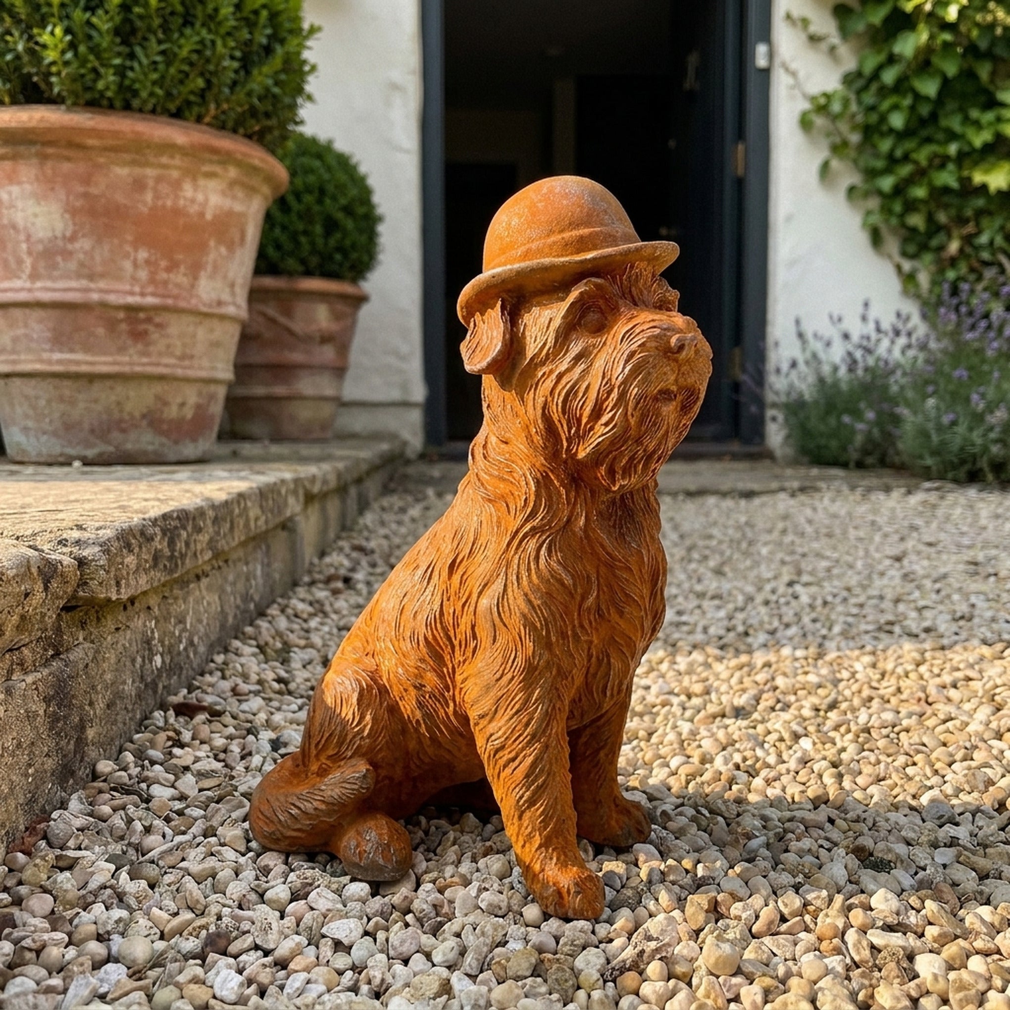Mr Capone rust cast iron terrier statue in a bowler hat, on gravel beside a terracotta pot