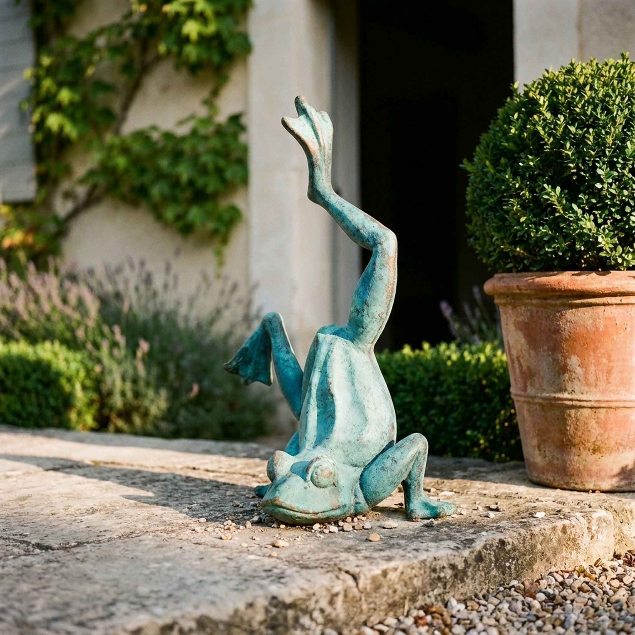 Major Ribbit in bright verdigris cast iron, doing a handstand with one leg raised, beside a terracotta pot