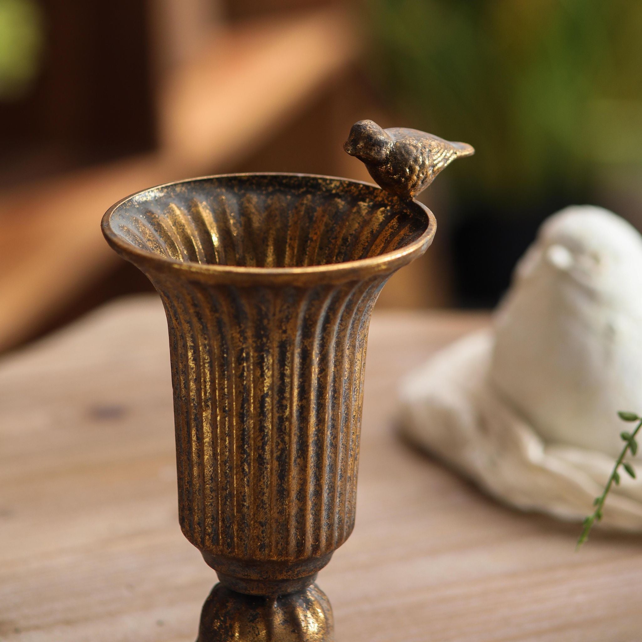 Fernande close-up of the cast bird perched on the fluted rim and the aged gold finish.