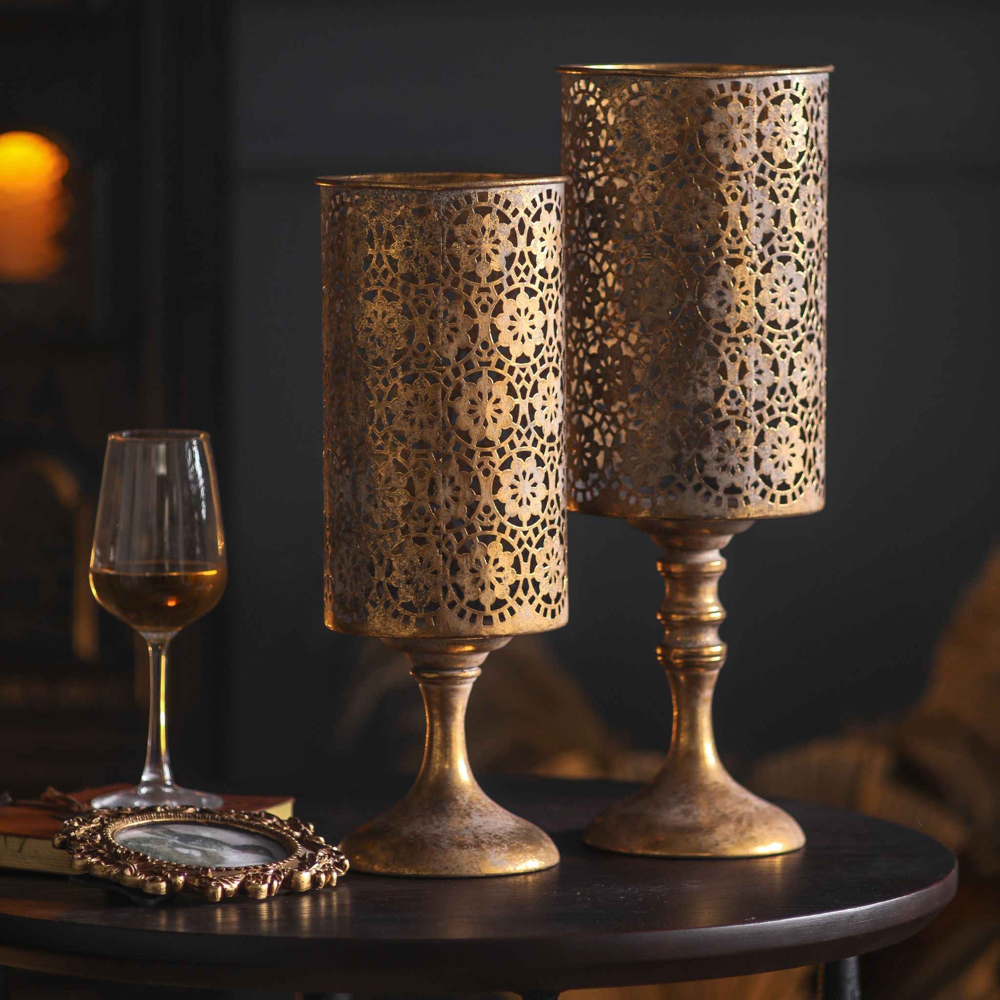 Paros pierced metal pedestal candle holder pair, 44.5cm and 38cm, unlit showing the lace pattern and goblet bases