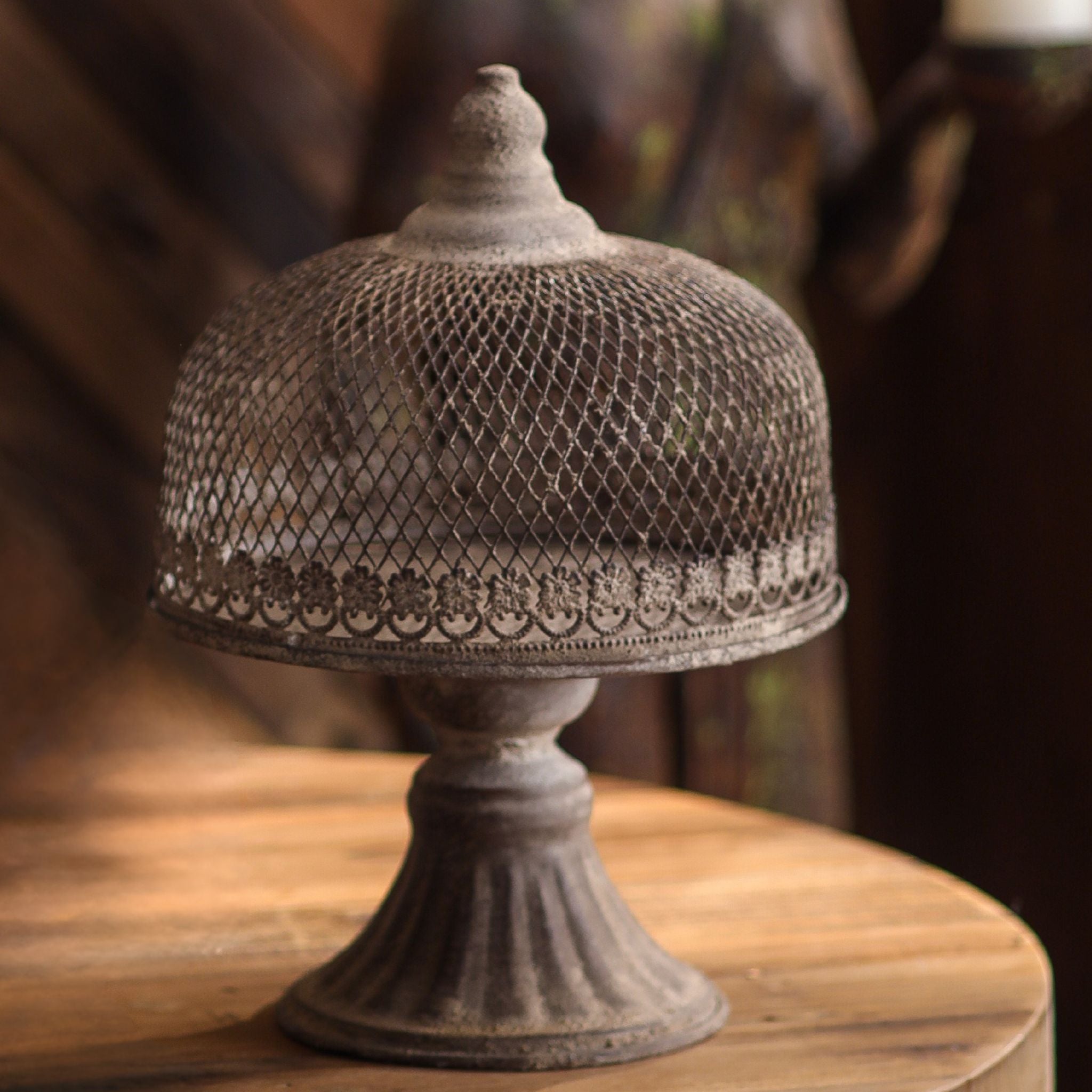 Leandro large pedestal cloche showing the woven mesh dome, floral band, and turned finial