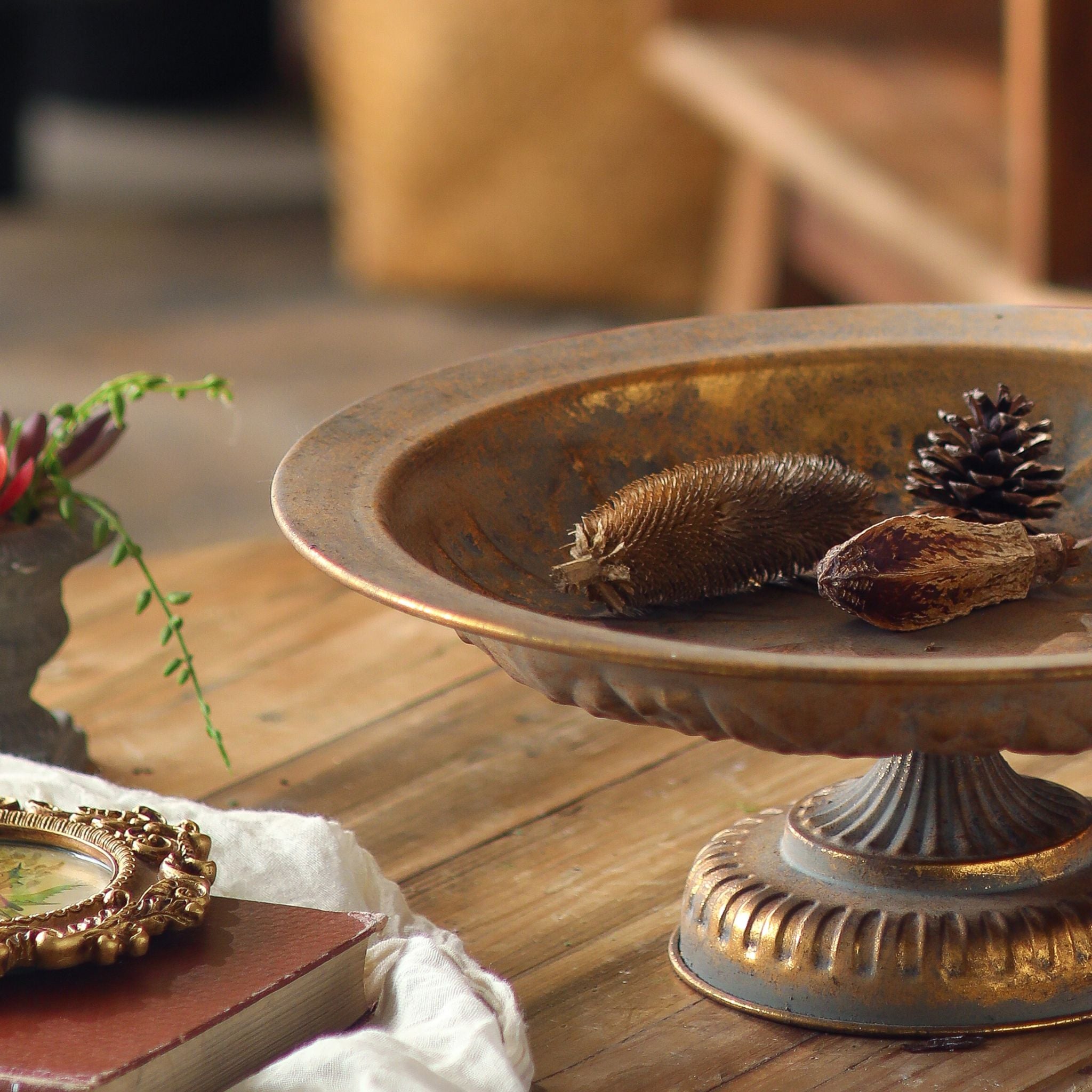 Menton pedestal bowl close crop showing the rust-mottled gold finish