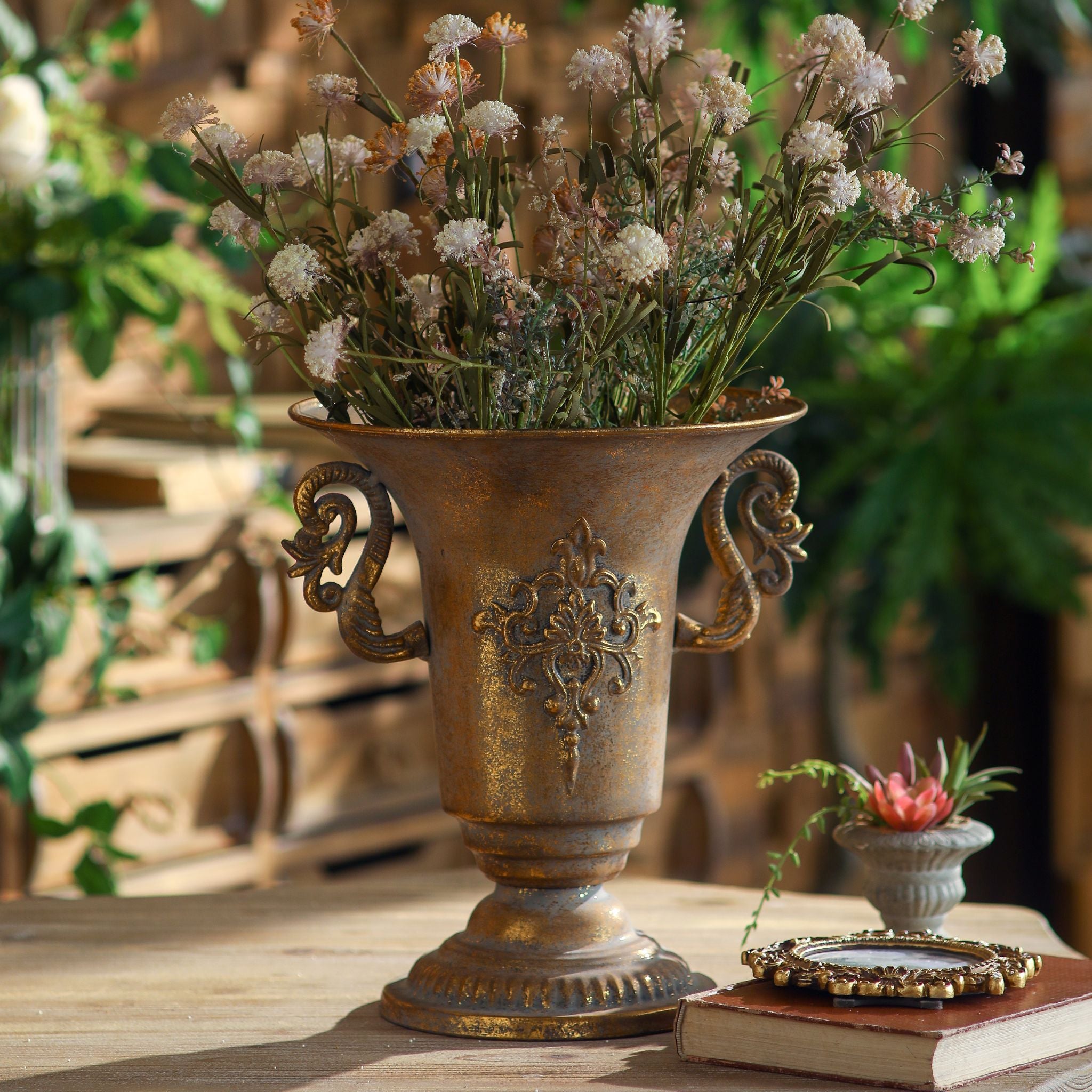Capri French Provincial urn vase in burnished gold with scroll handles holding dried wildflowers. Hero.