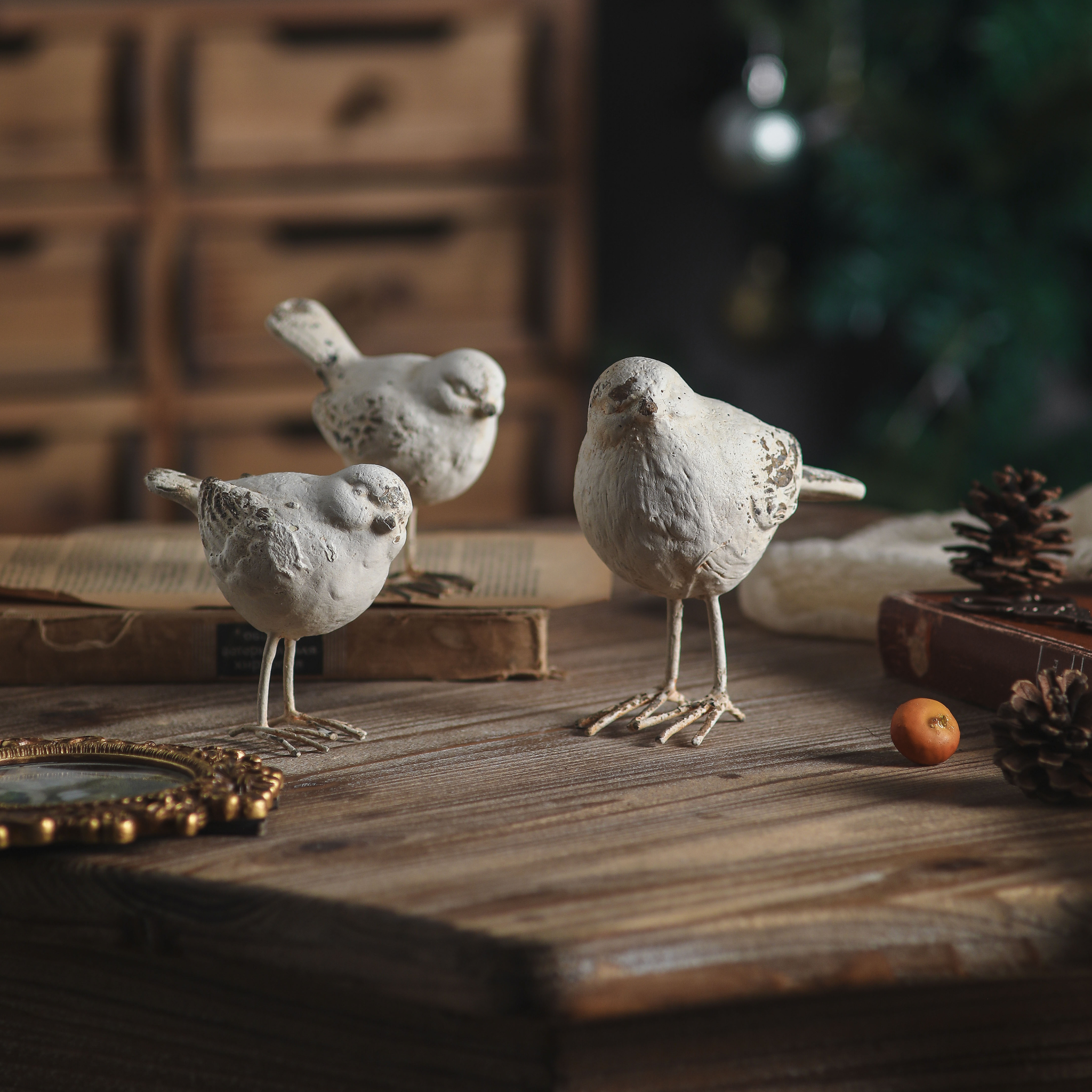 Gia bird figurines styled among vintage books and pine cones