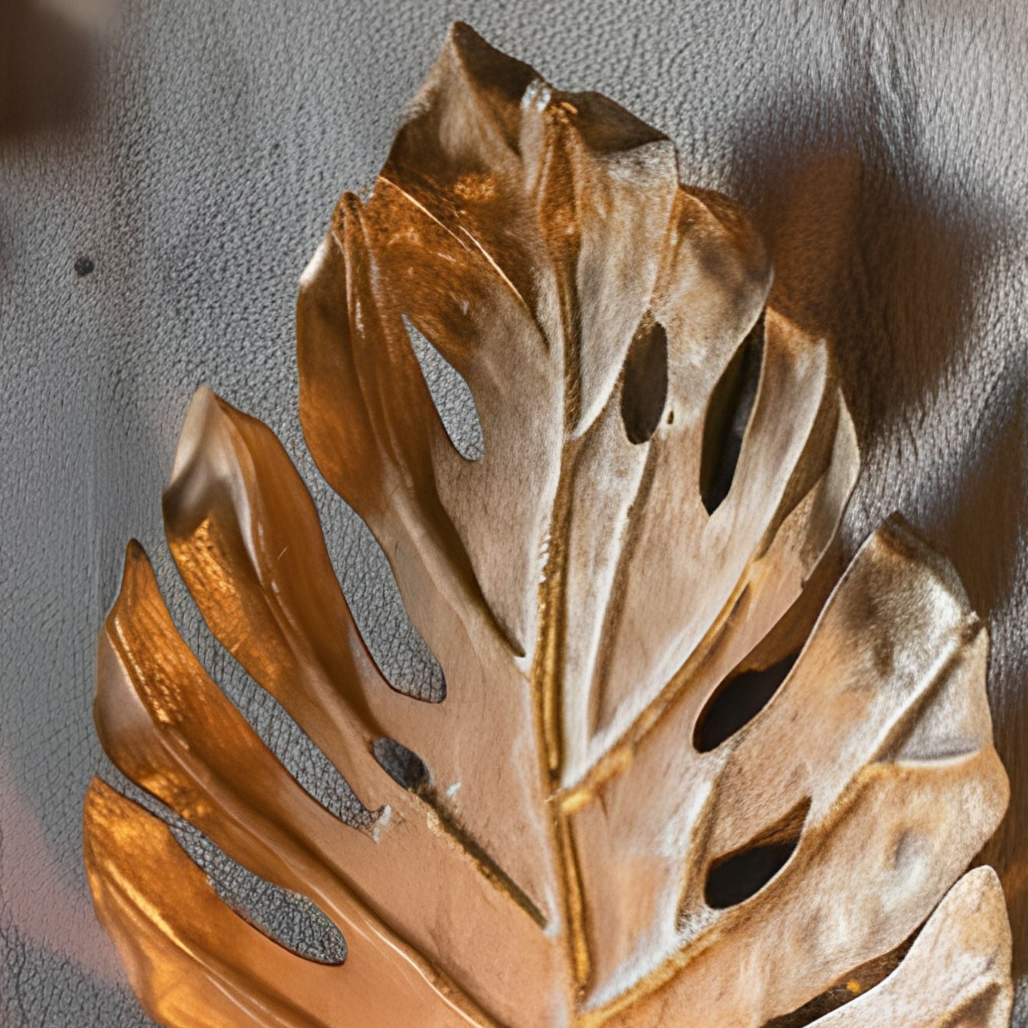 Lower half of the Adele wall sconce showing the candle cup and scrolled arm with a lit pillar candle below the split leaf.