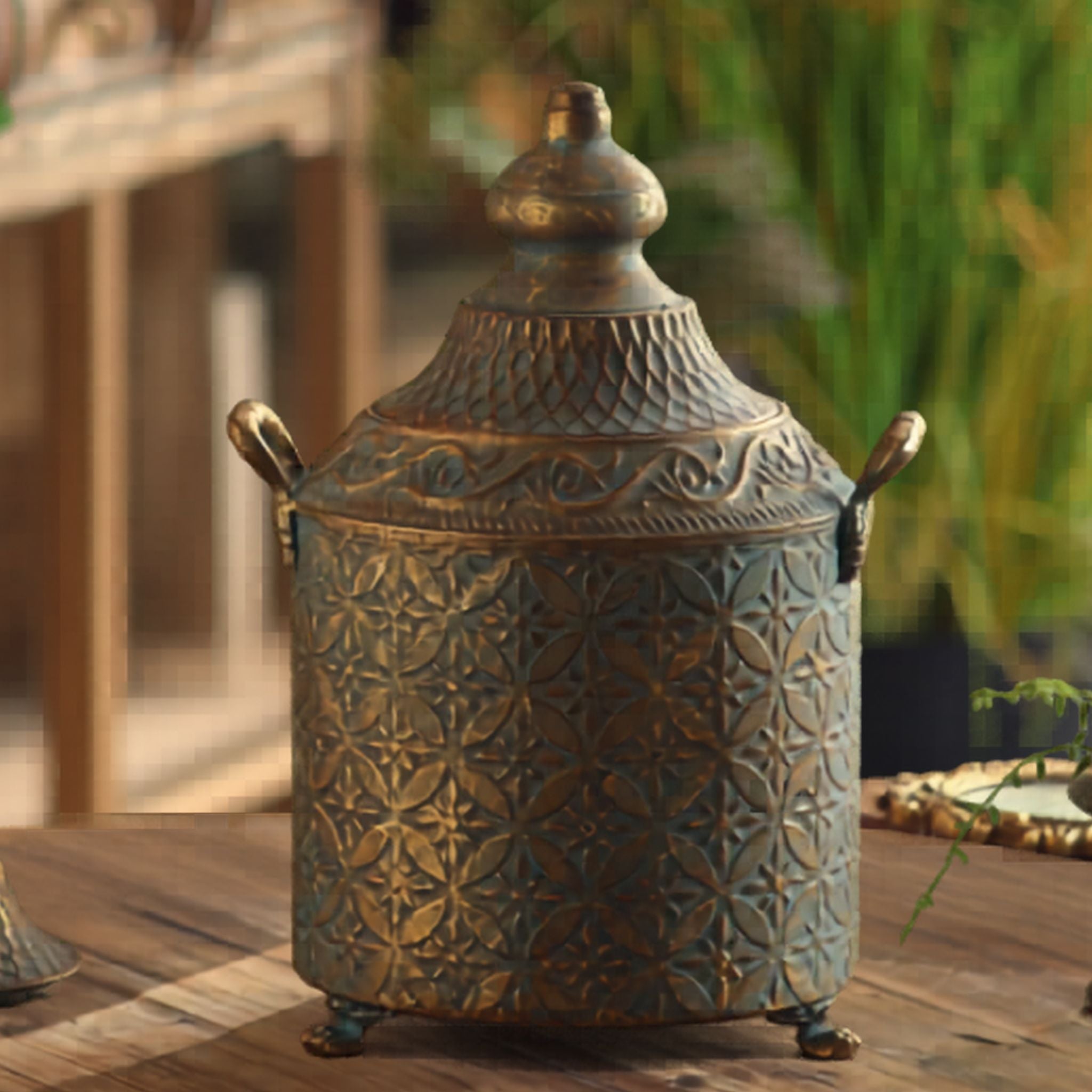 Agathe French Provincial lidded canister in antique gold over verdigris embossed metal, with domed finial lid and twin handles. Hero.