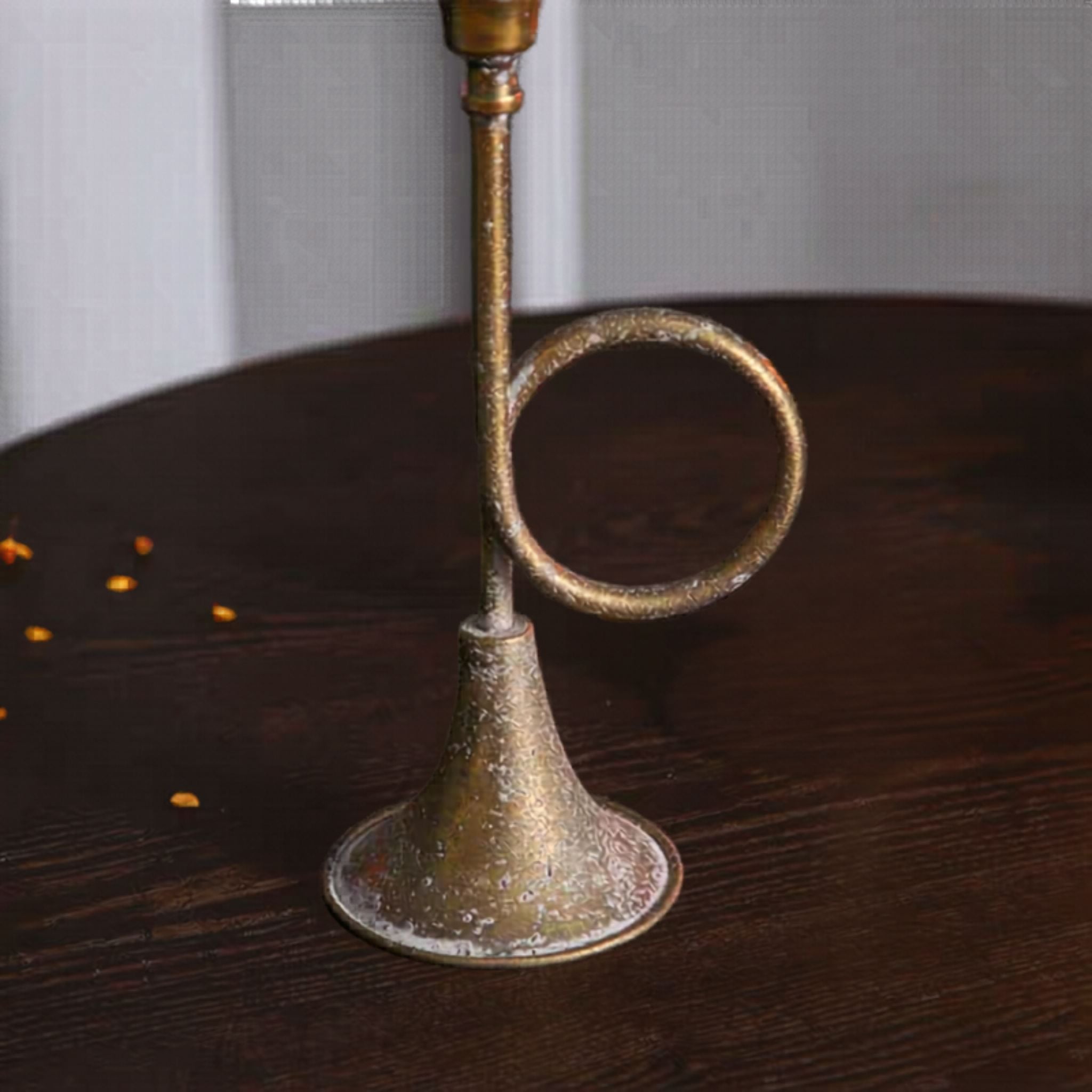 Close detail of the flared foot and coiled loop, aged metal with mottled antique gold.