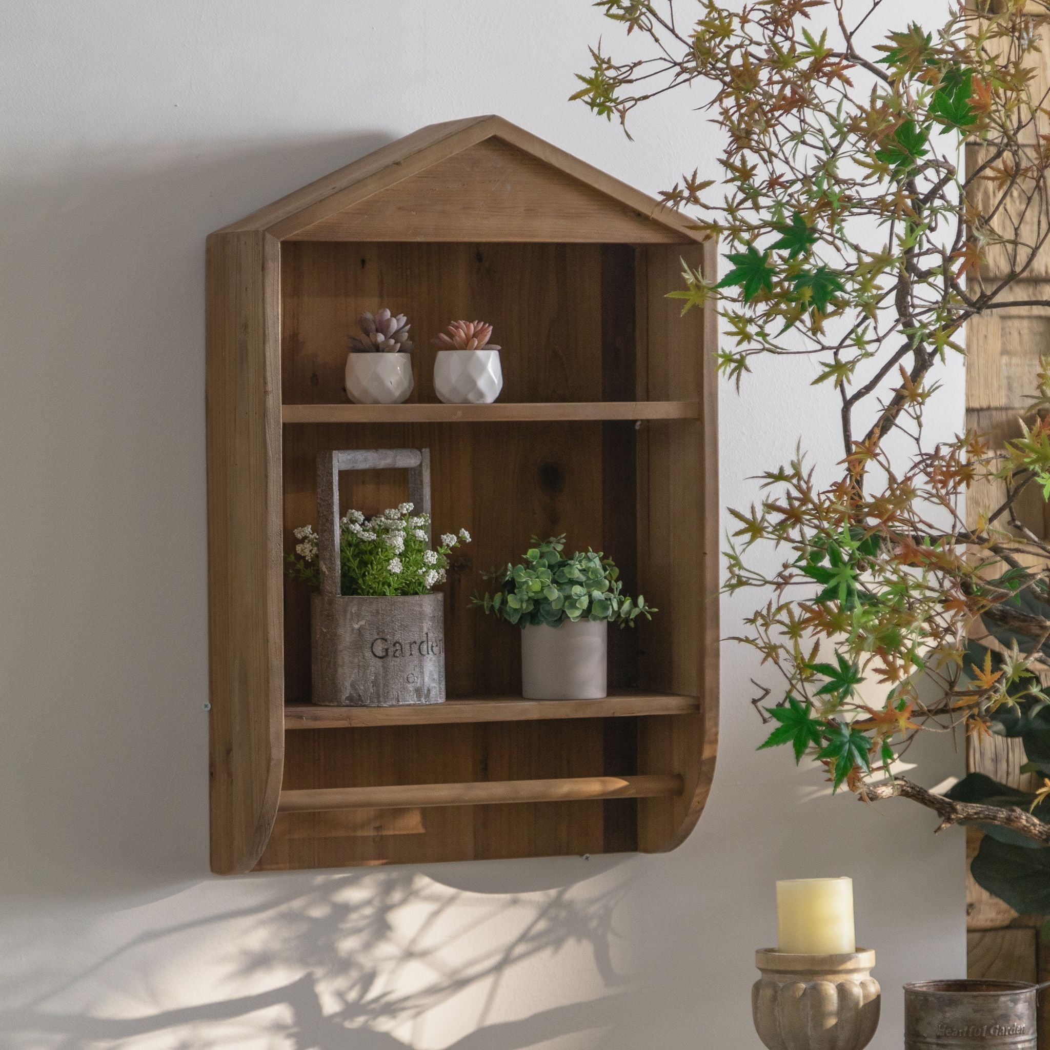 Alderic house-shaped wall shelf styled with plants in a rustic cottage setting.