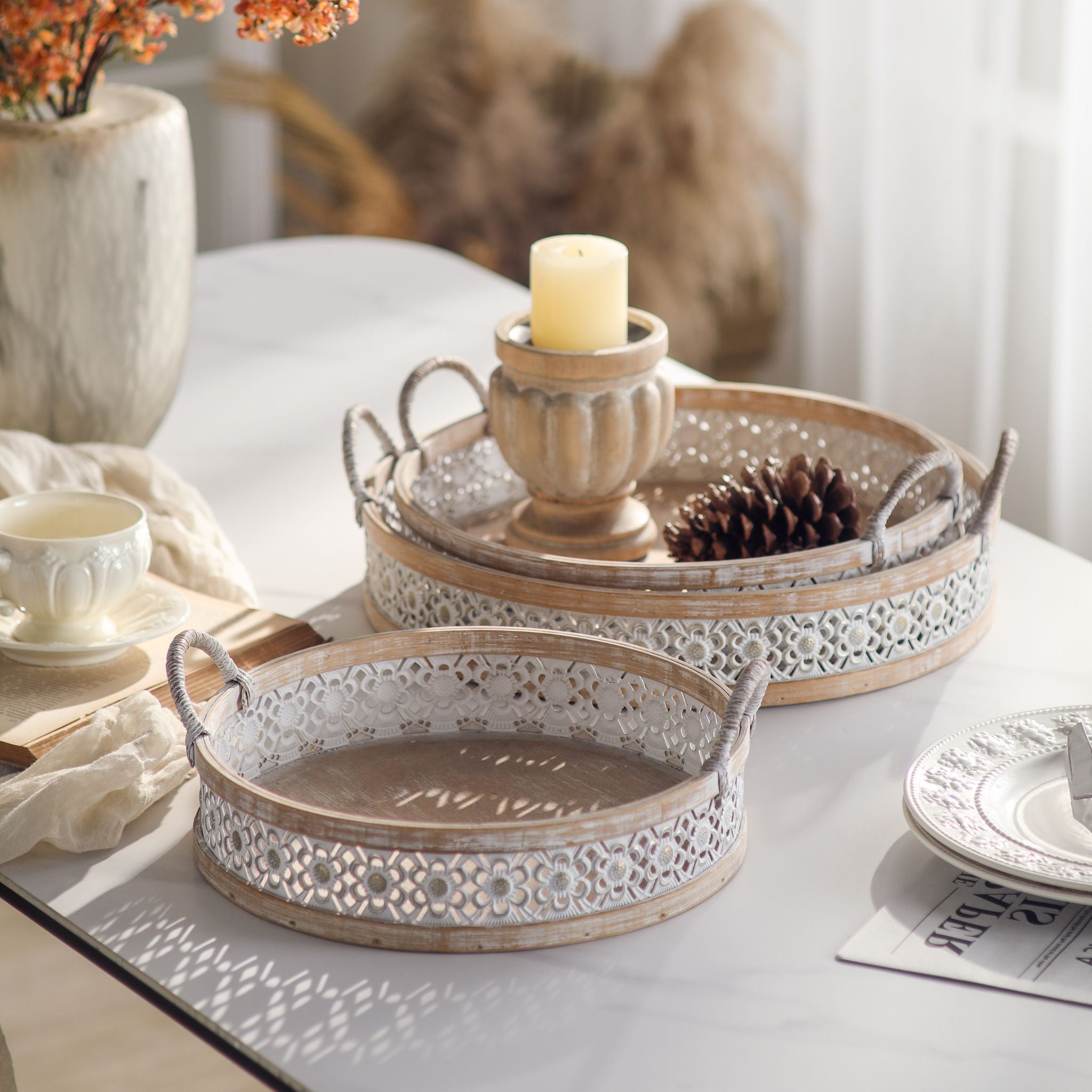 Alexandrine round trays styled on a table with a candle and dried blooms, whitewashed wood frames and rope handles