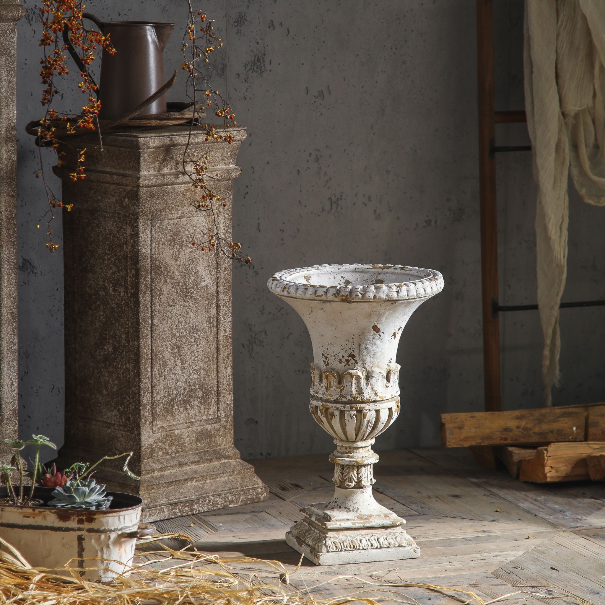 Anaïs urn planter shown empty in a rustic setting, full view of the trumpet shape and pedestal.