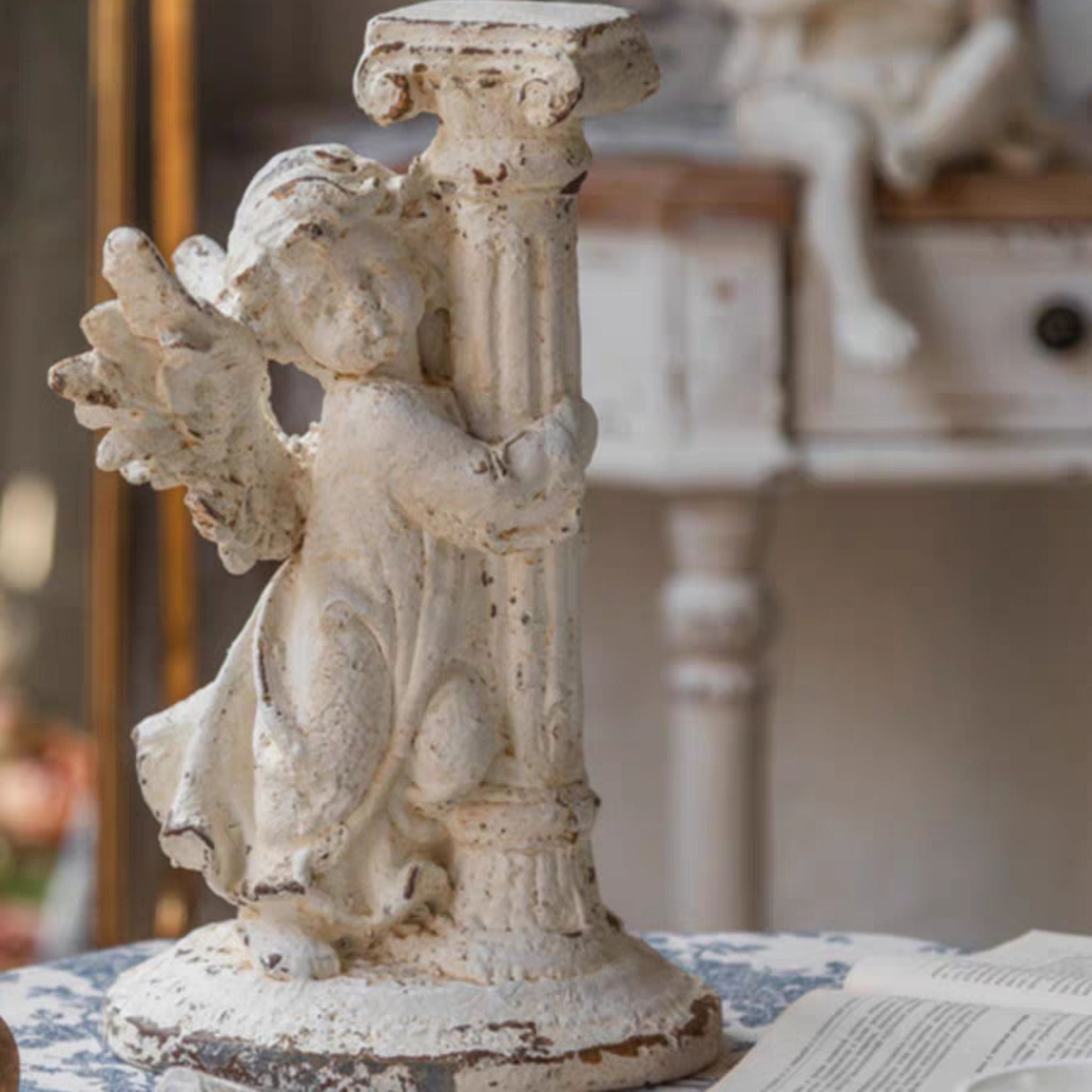 André cherub sculpture, full figure from the side on its oval base, winged child wrapped around the fluted column.