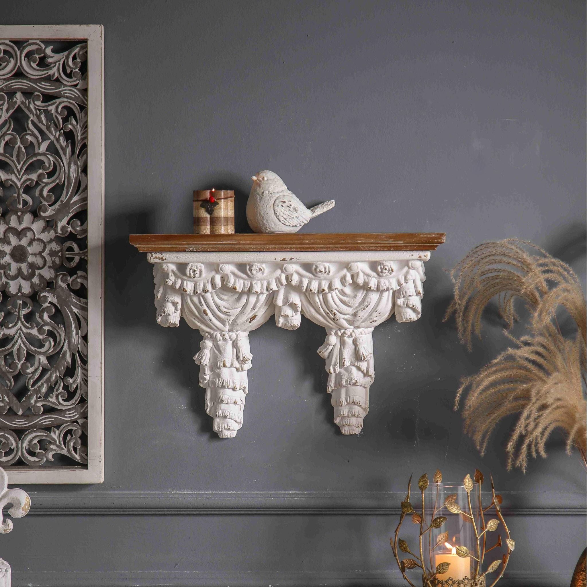 Annie French Provincial draped curtain wall shelf in distressed whitewash with carved swag apron and timber top, styled on a charcoal wall with a small white bird and dried pampas grass. Hero.