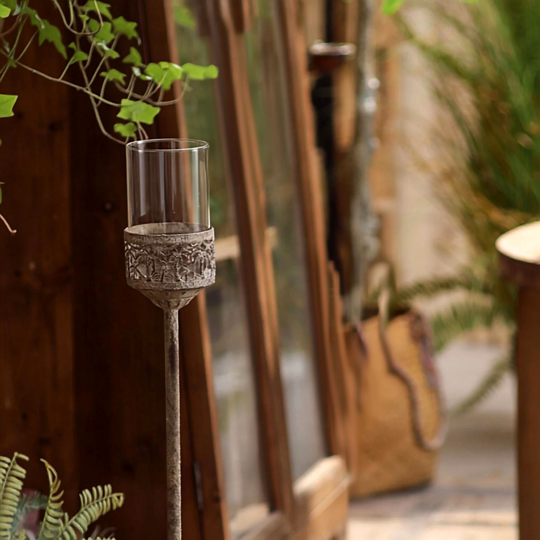 Anselme floor candle holder standing on a timber verandah beside a doorway