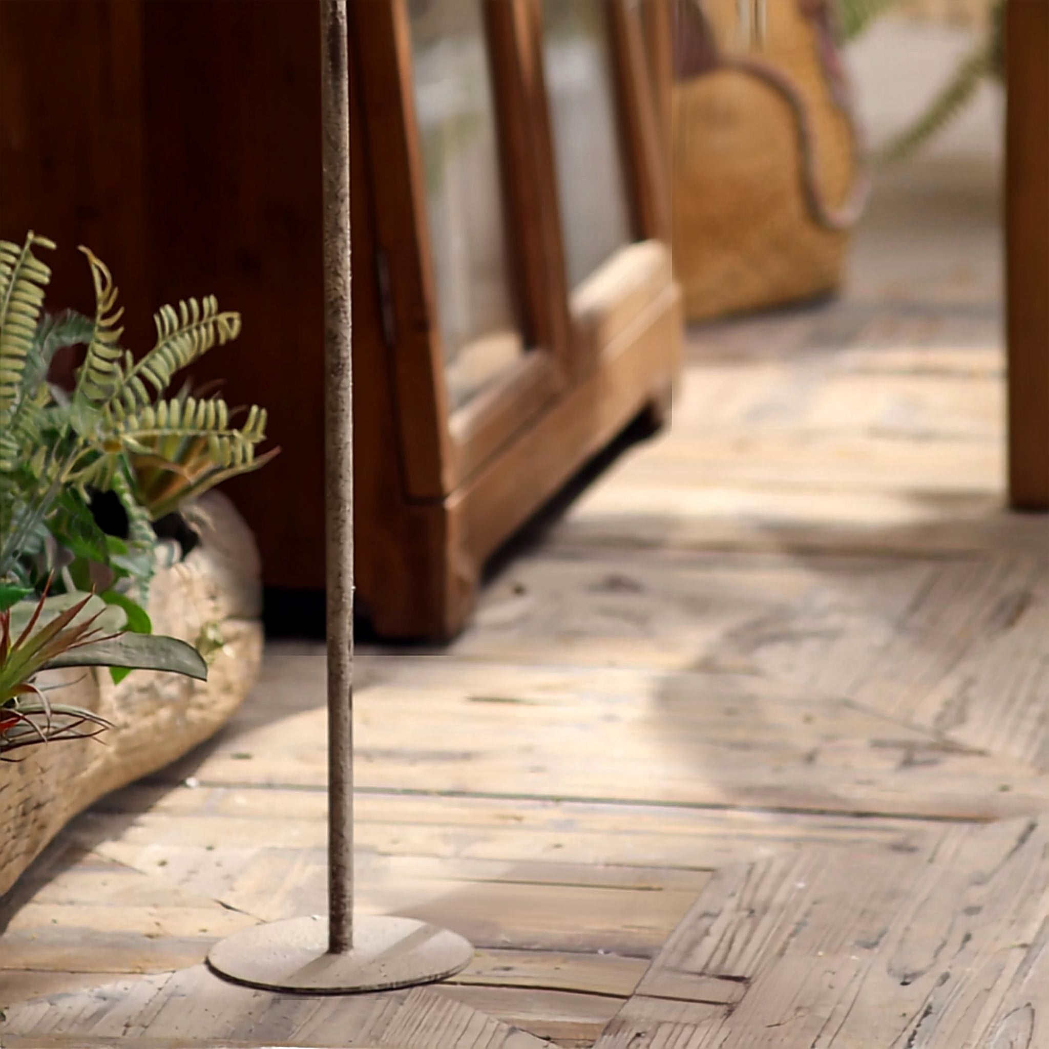 Base detail of the aged metal floor candle holder on timber decking