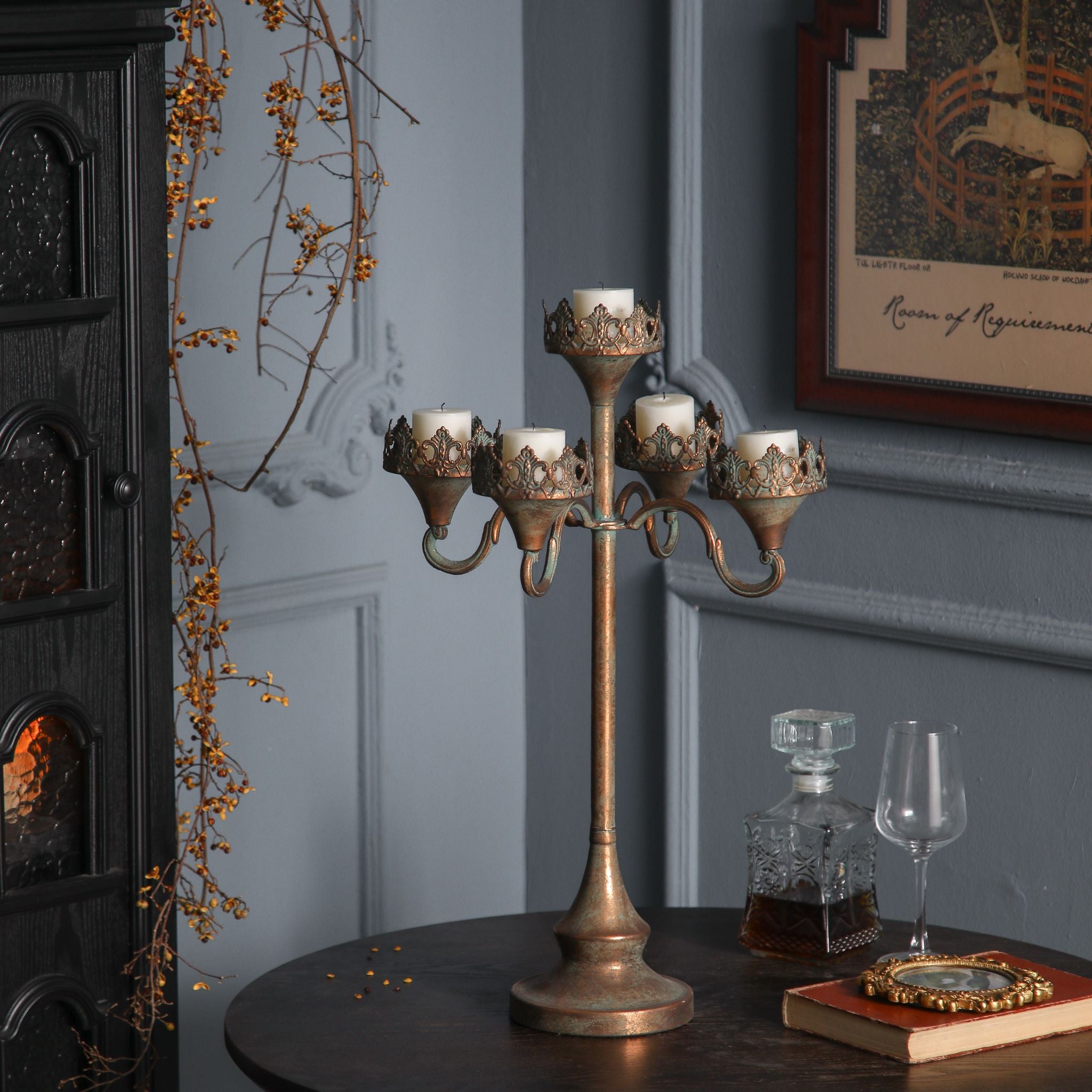 Emma antique gold five-light candelabra, unlit cream pillar candles, showing the tall stem, stepped arms and crown collars.