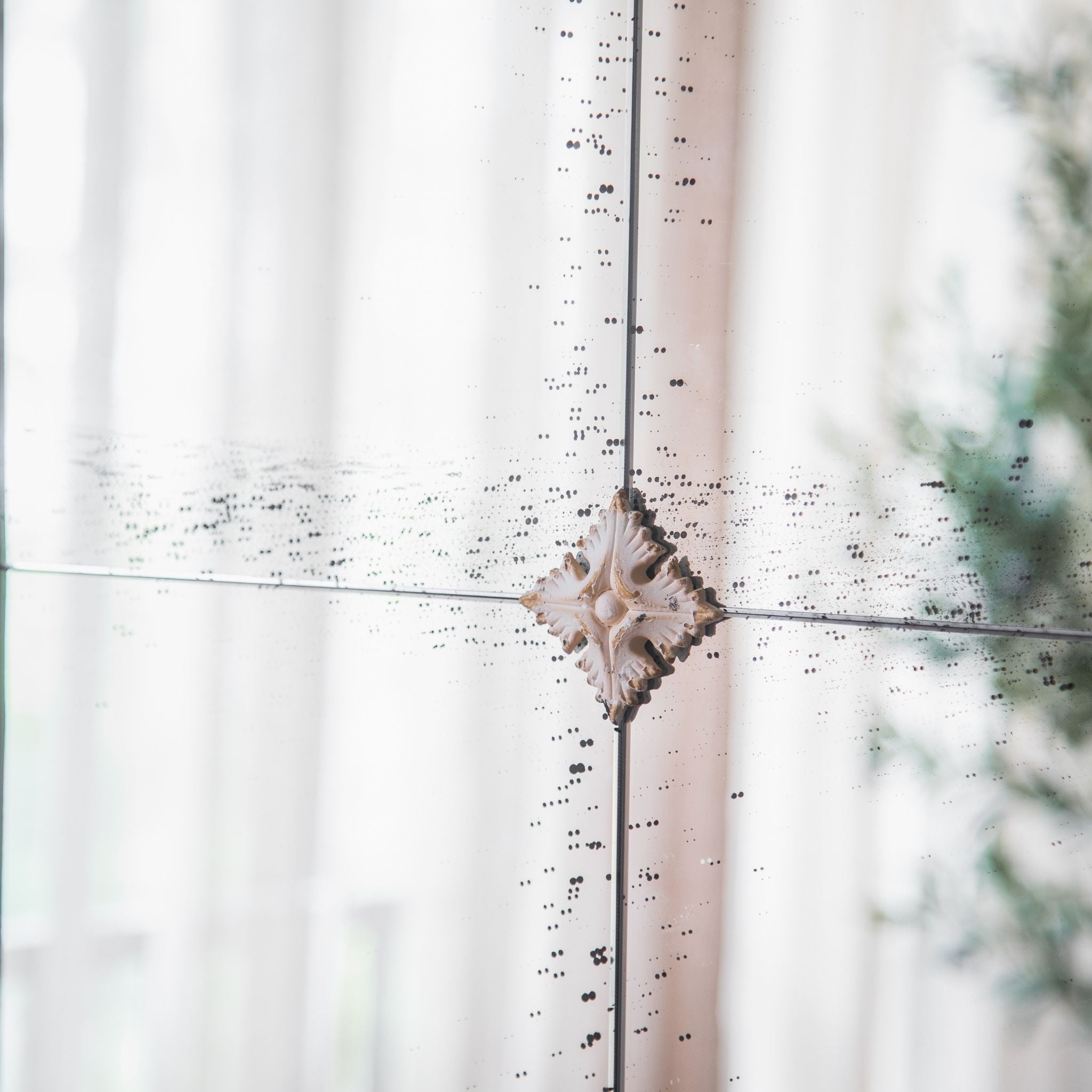 Detail of the Marion mirror's antiqued foxed glass and moulded rosette medallion at the pane join