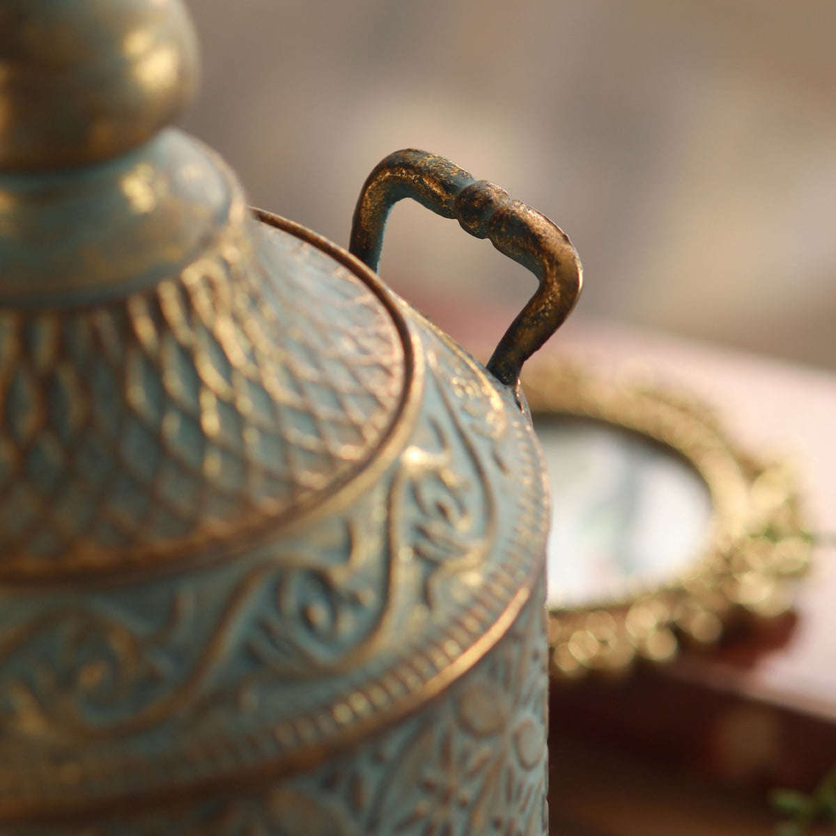 Aria canister detail of one twin handle and the embossed floral lattice pattern.