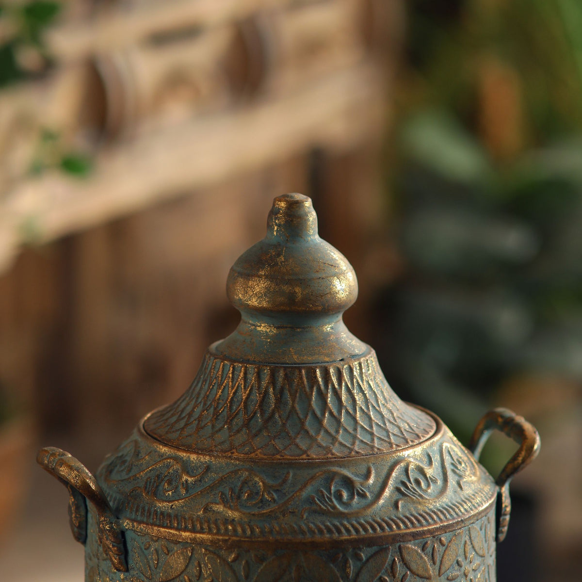 Aria canister close-up of the domed lid, turned finial and cross-hatched collar in antique gold.