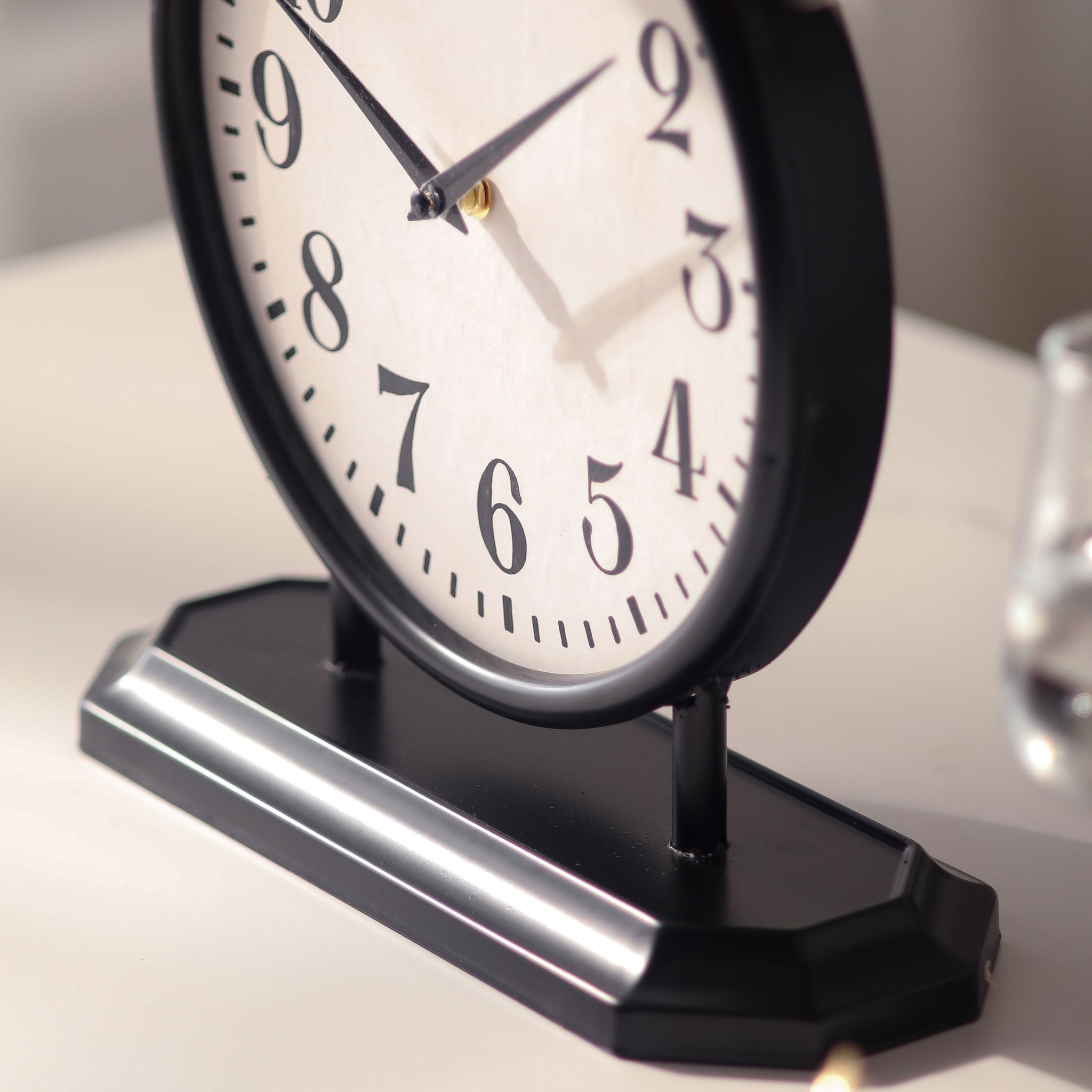 Angled detail of the Patricia table clock face and black metal base