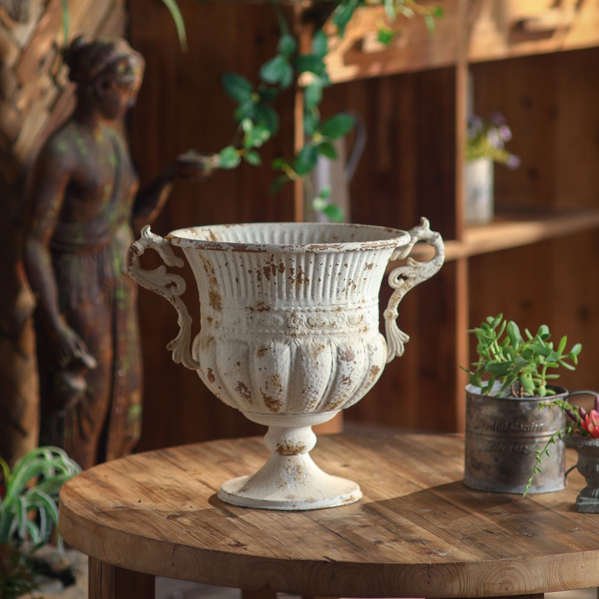 Benoît urn planter shown empty in a rustic garden setting, full view of the handled shape.