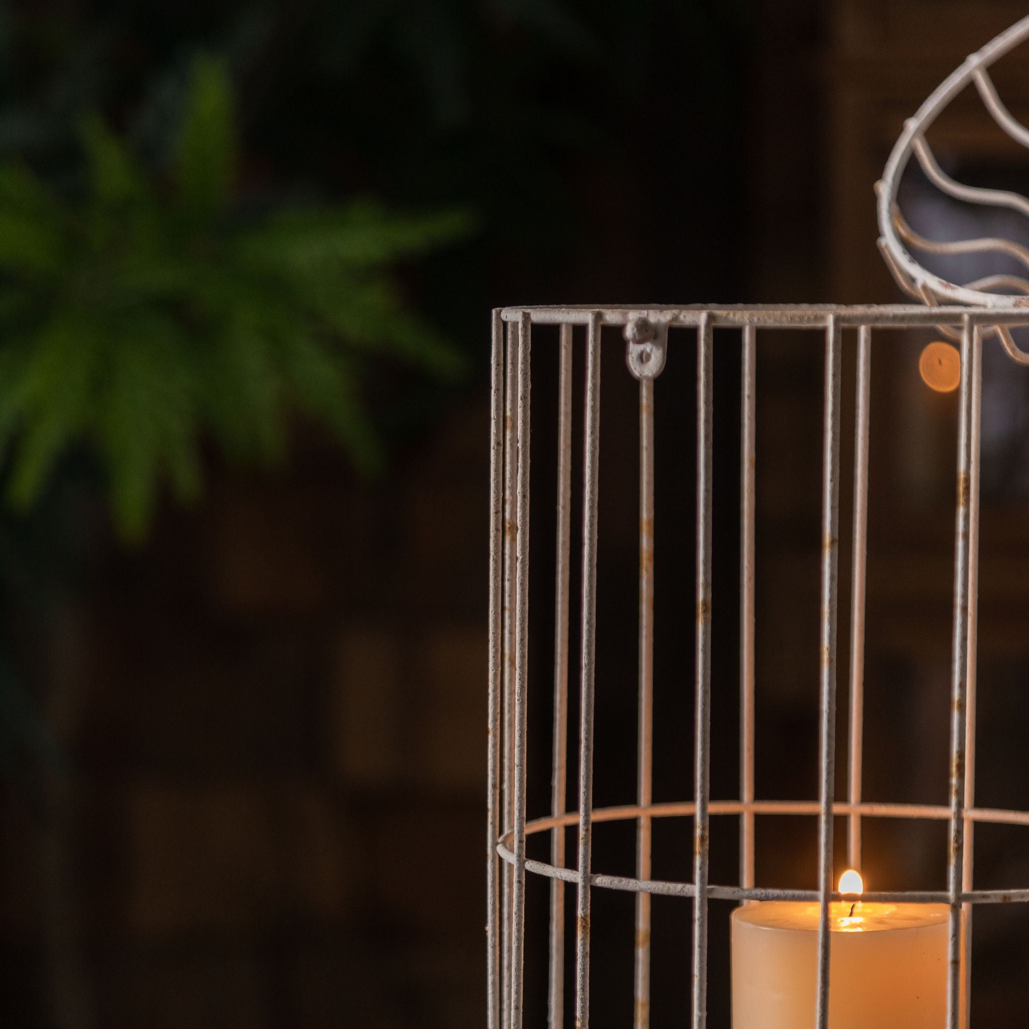 Bernard birdcage candle lantern wire cage close detail with lit candle glow behind