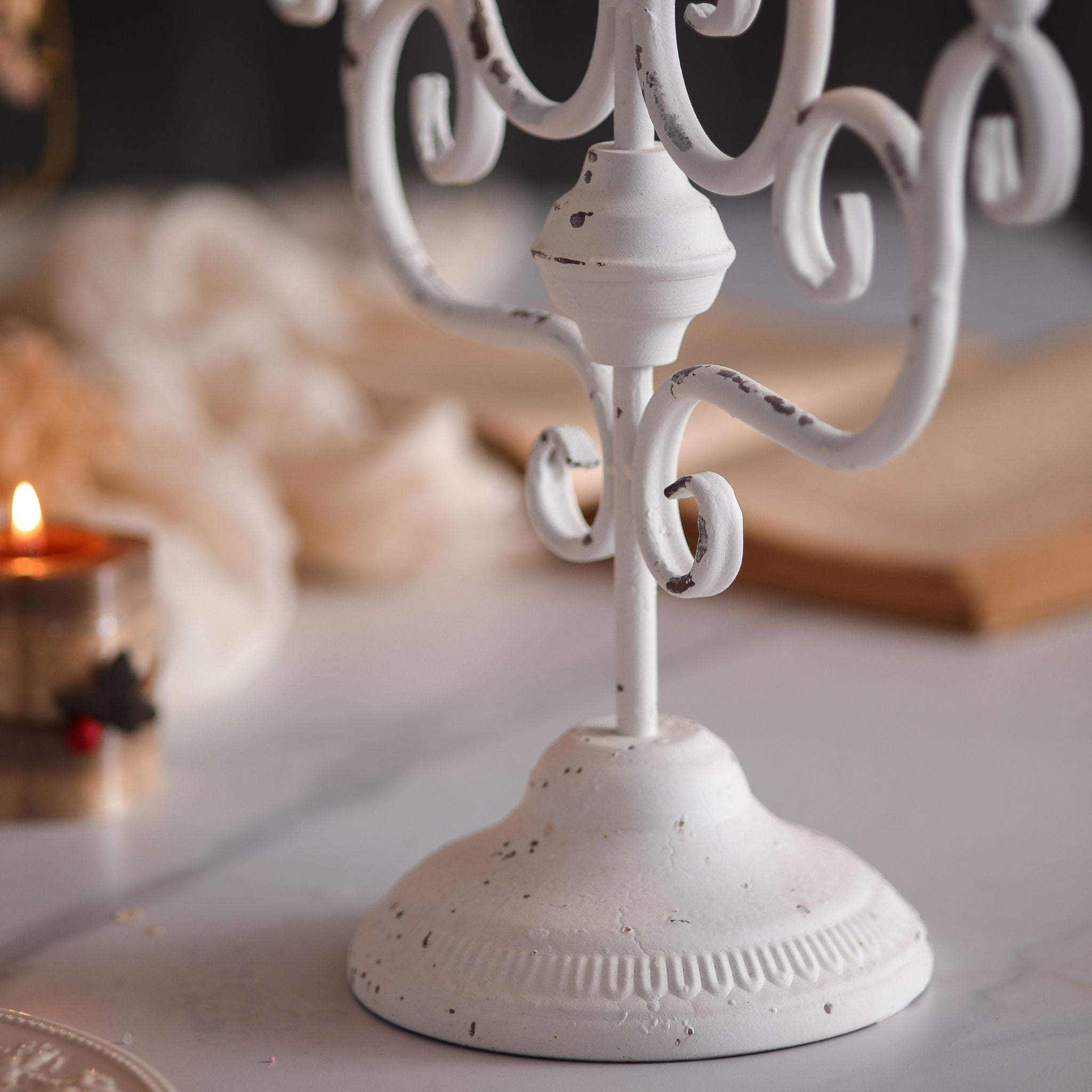 Close-up of the fluted base, turned stem, and scrollwork showing the worn distressed white finish.