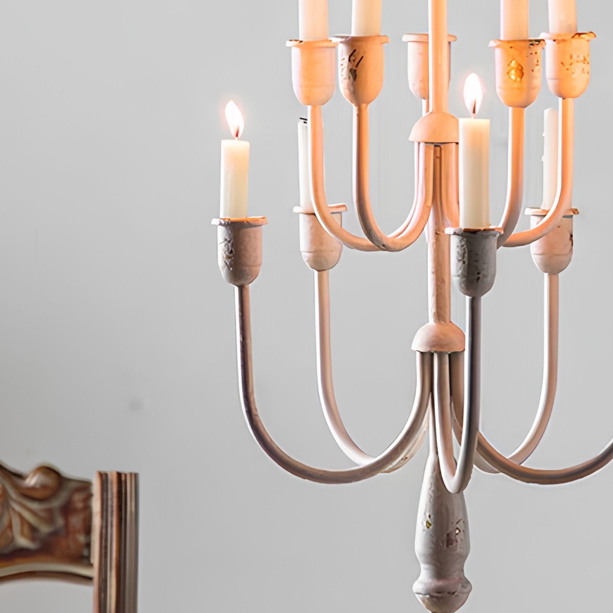 Close view of the two tiers of curved arms and cups in worn distressed cream holding tapers.