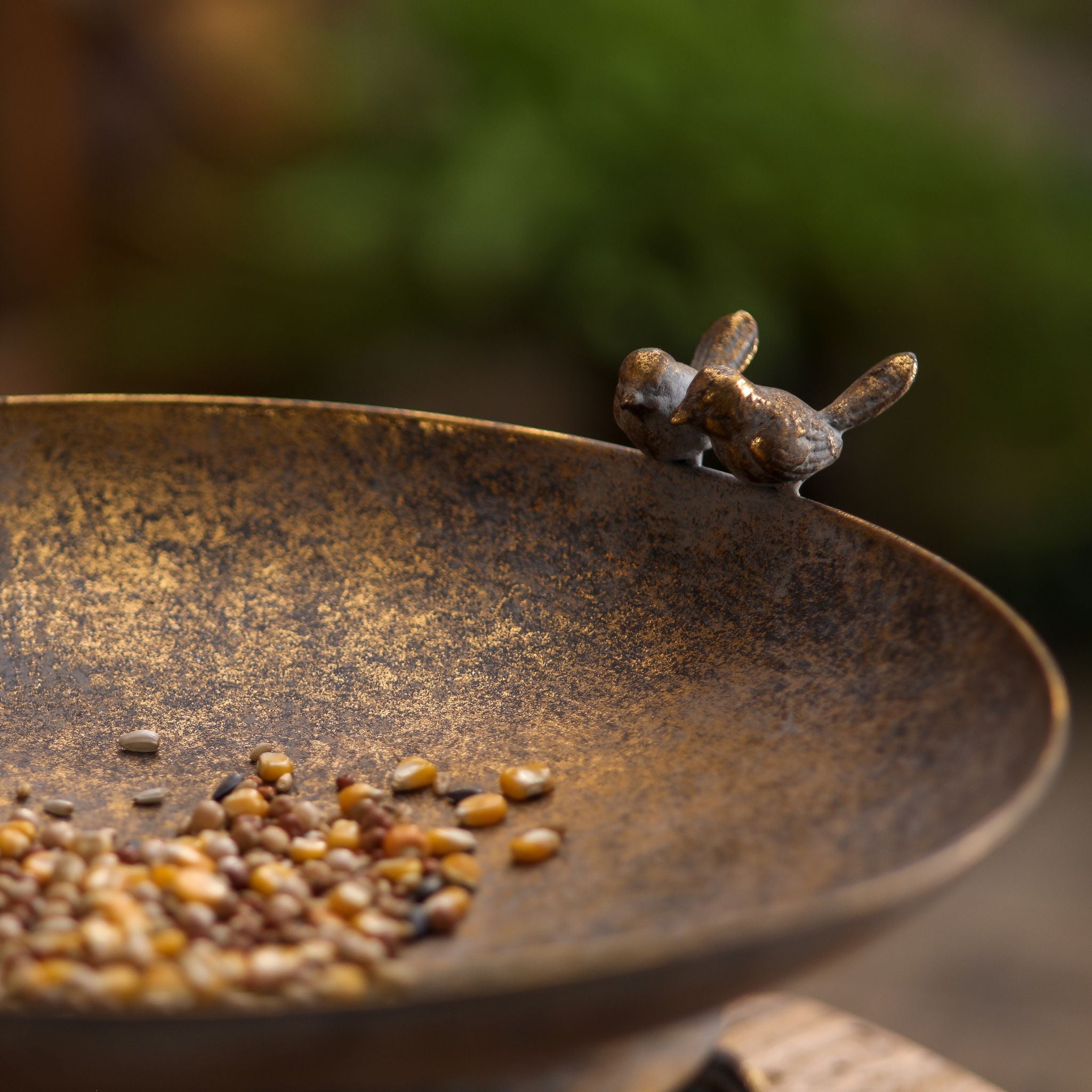 Detail of the pair of cast bird figures on the rim of the Chandler dish, with seed in the bronze bowl.
