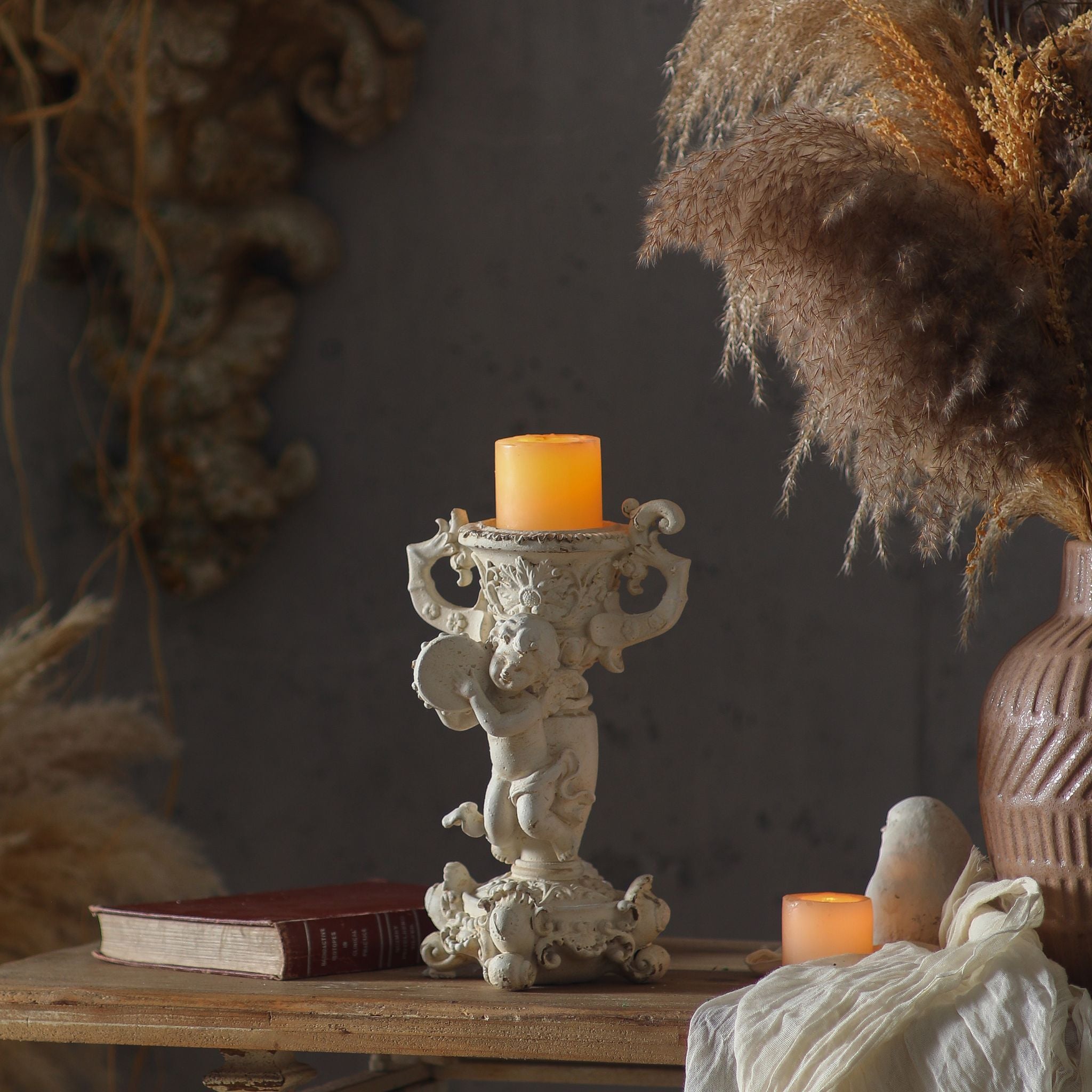 Claude cherub candle holder lit with a pillar candle in a styled French Provincial setting