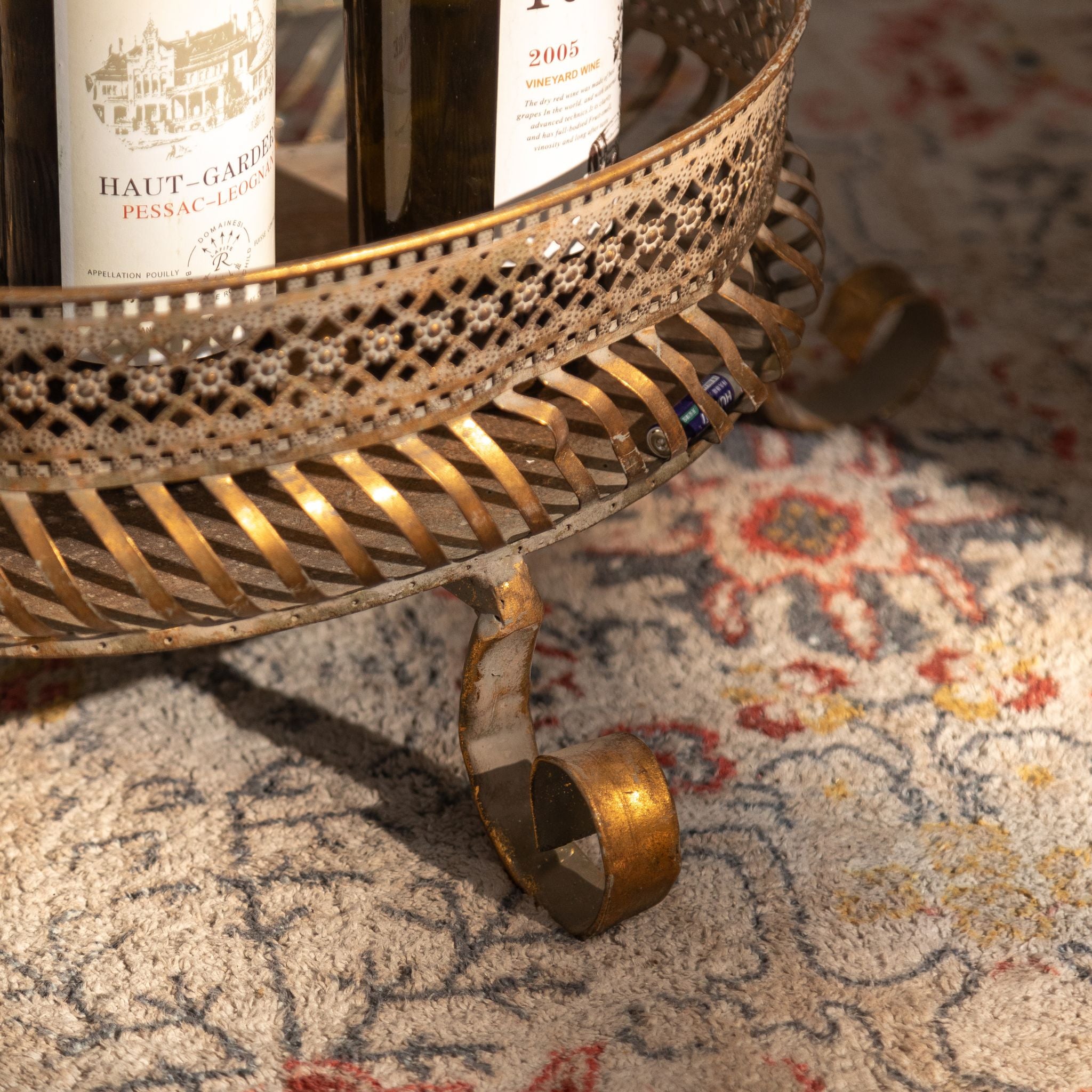 Detail of a curled scroll foot and ribbed tray band on the antique gold metal stand