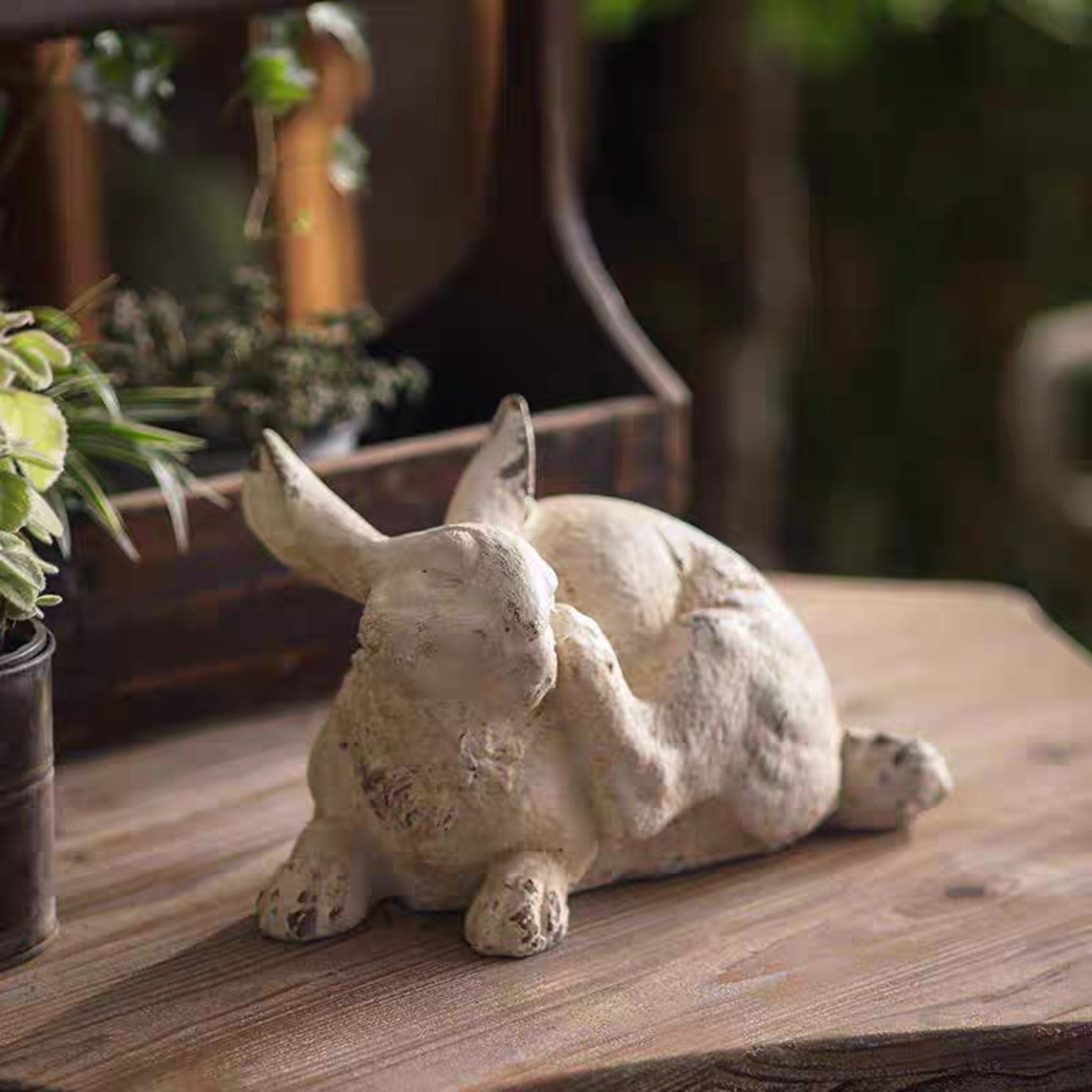Coco scratching rabbit statue, 30cm, back view showing playful tail-up pose and distressed patina