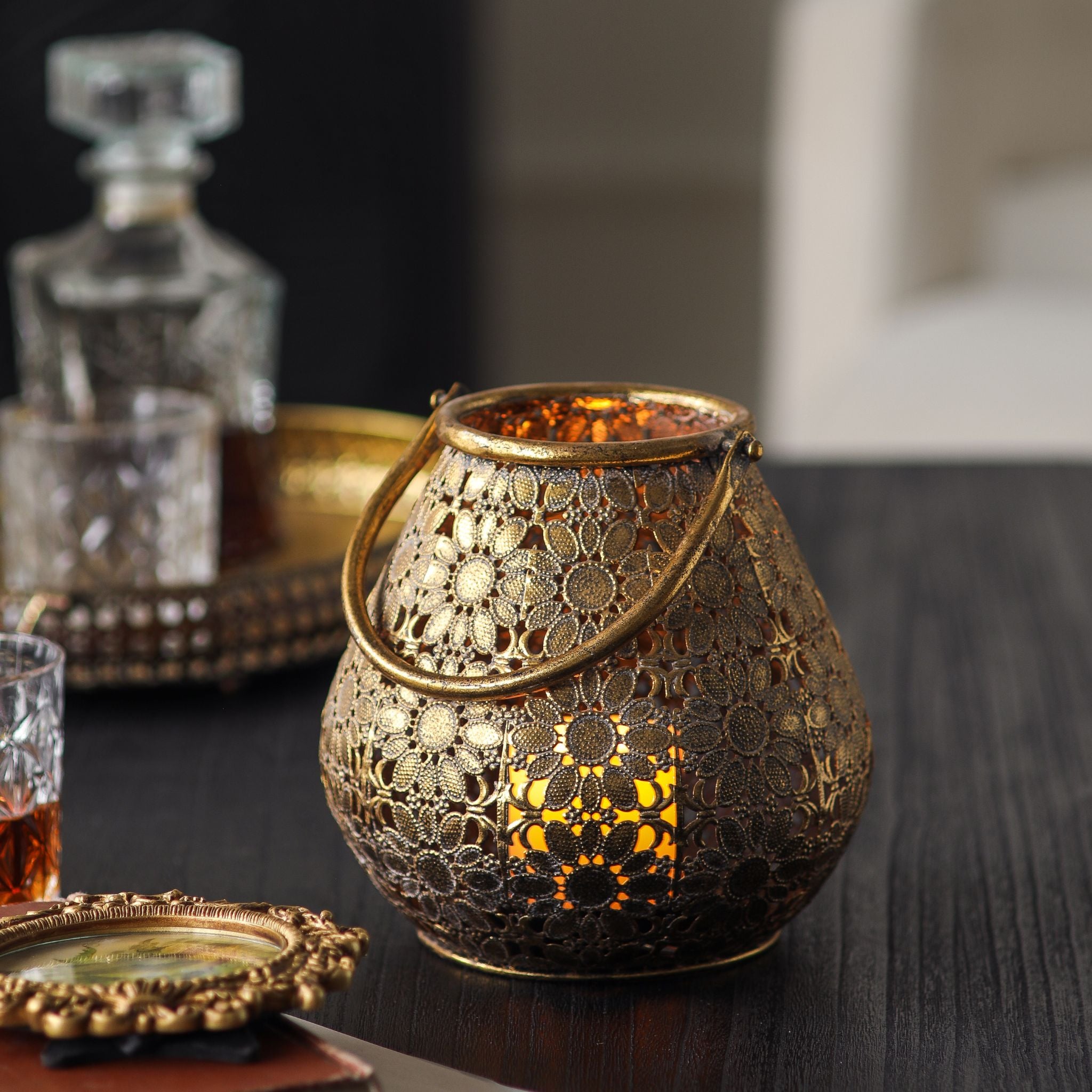 Single pierced antique gold lantern lit on a styled side table