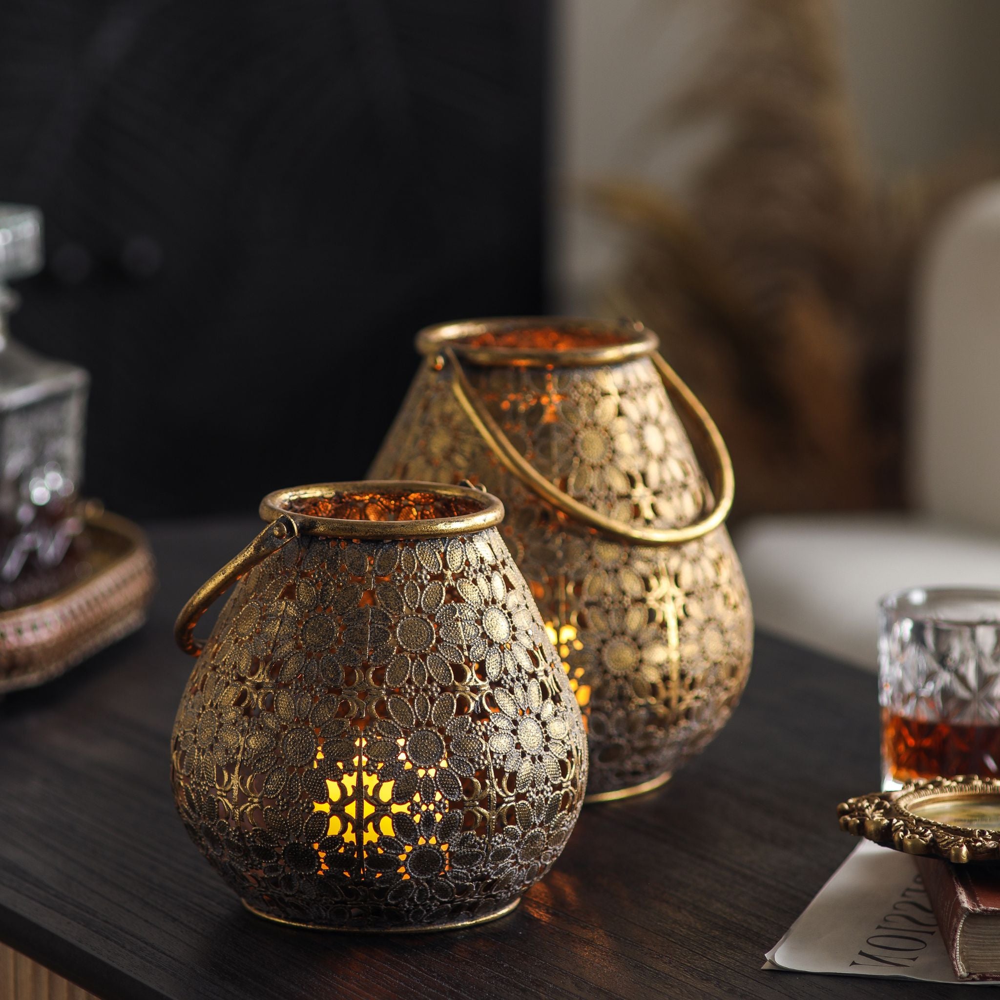 Colette set of two antique gold pierced lanterns with floral filigree, both lit on a dark table