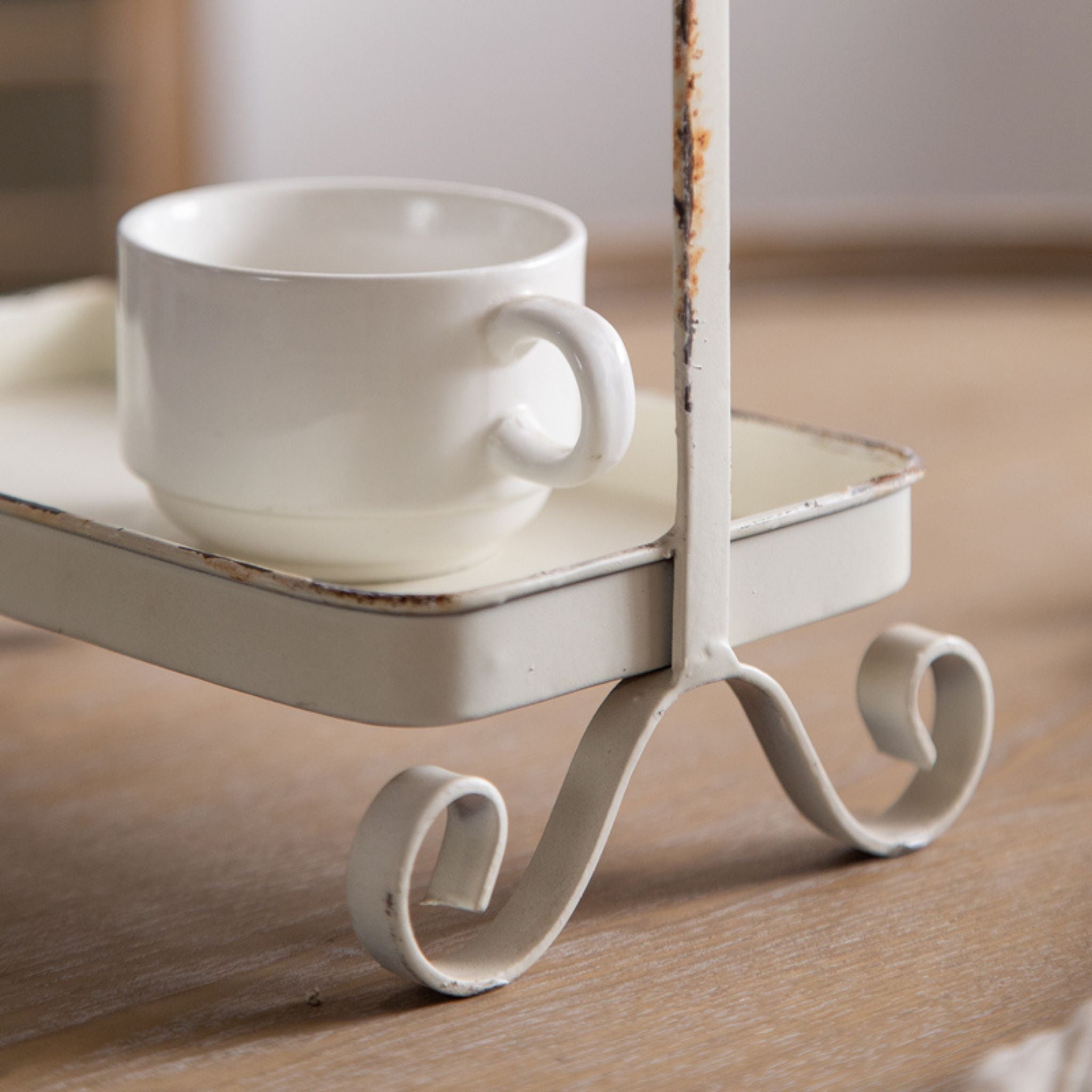 Detail of a curled scroll foot and rectangular tray on the distressed white stand