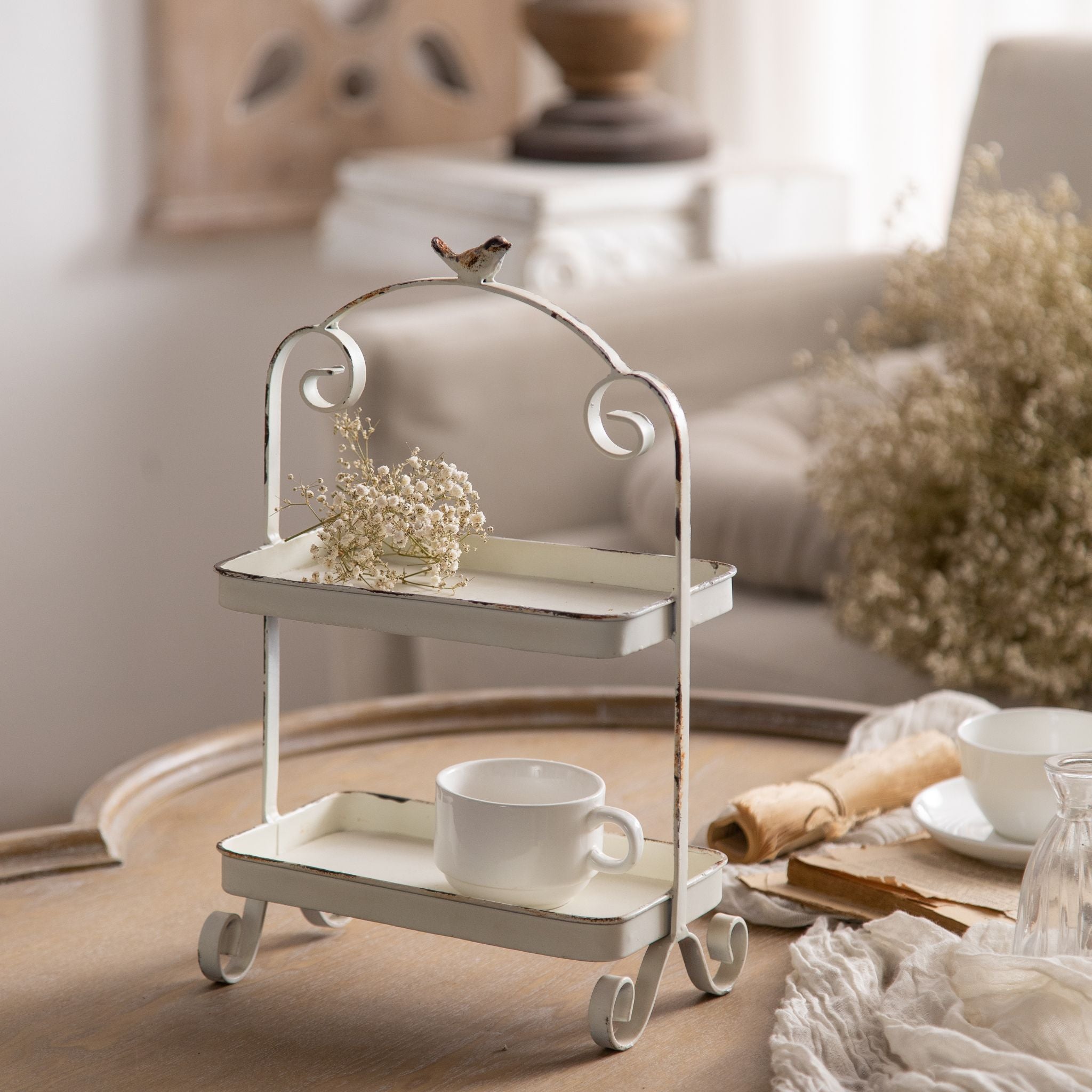 Small two tier rectangular tray stand in distressed white metal with a bird on top