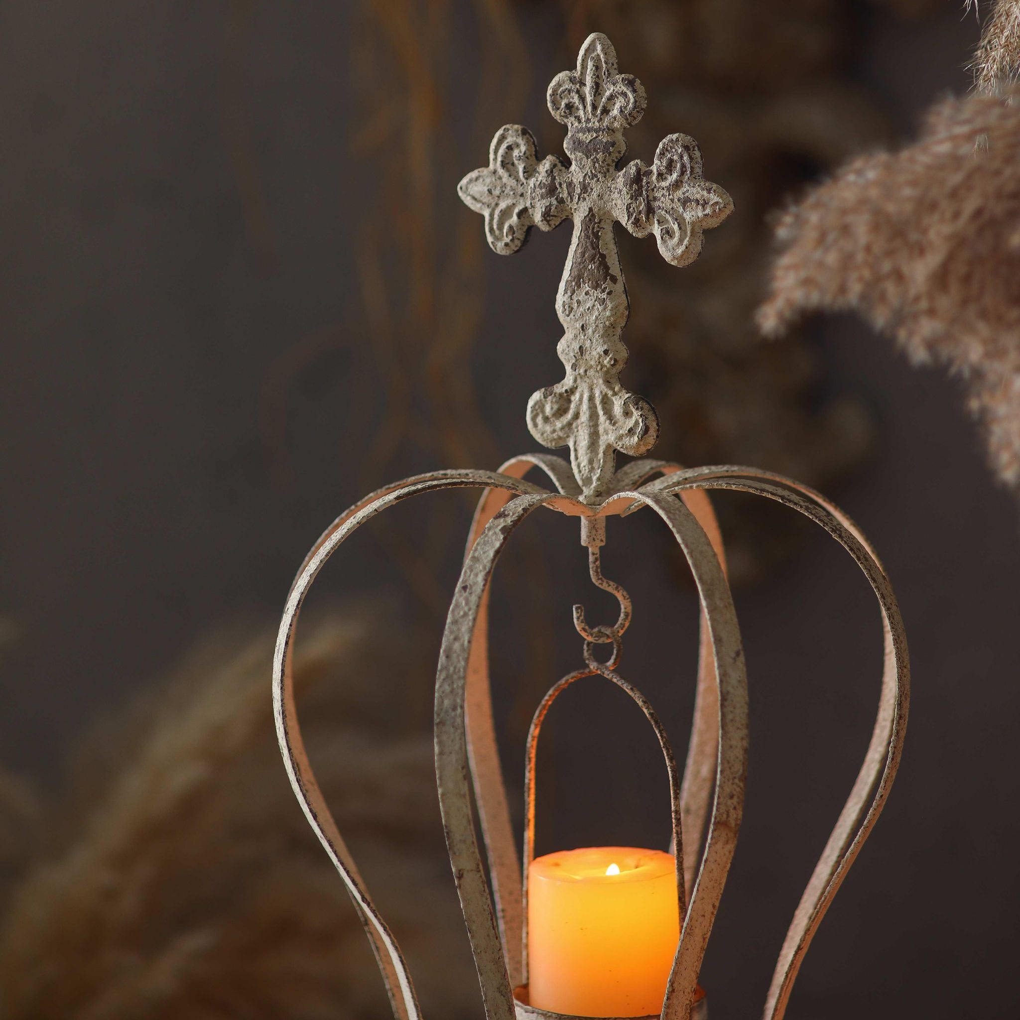 Close-up of the cross and fleur-de-lis finial above the hanging candle cradle