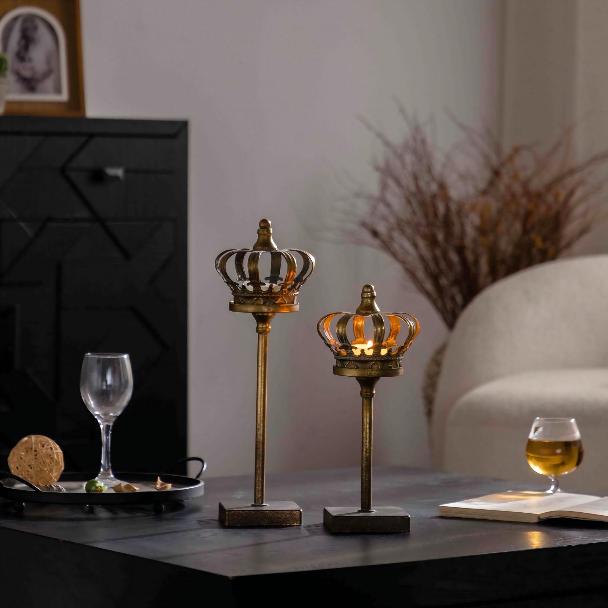 Crown tealight holder pair on a console with a lit tealight, styled with glassware and branches.