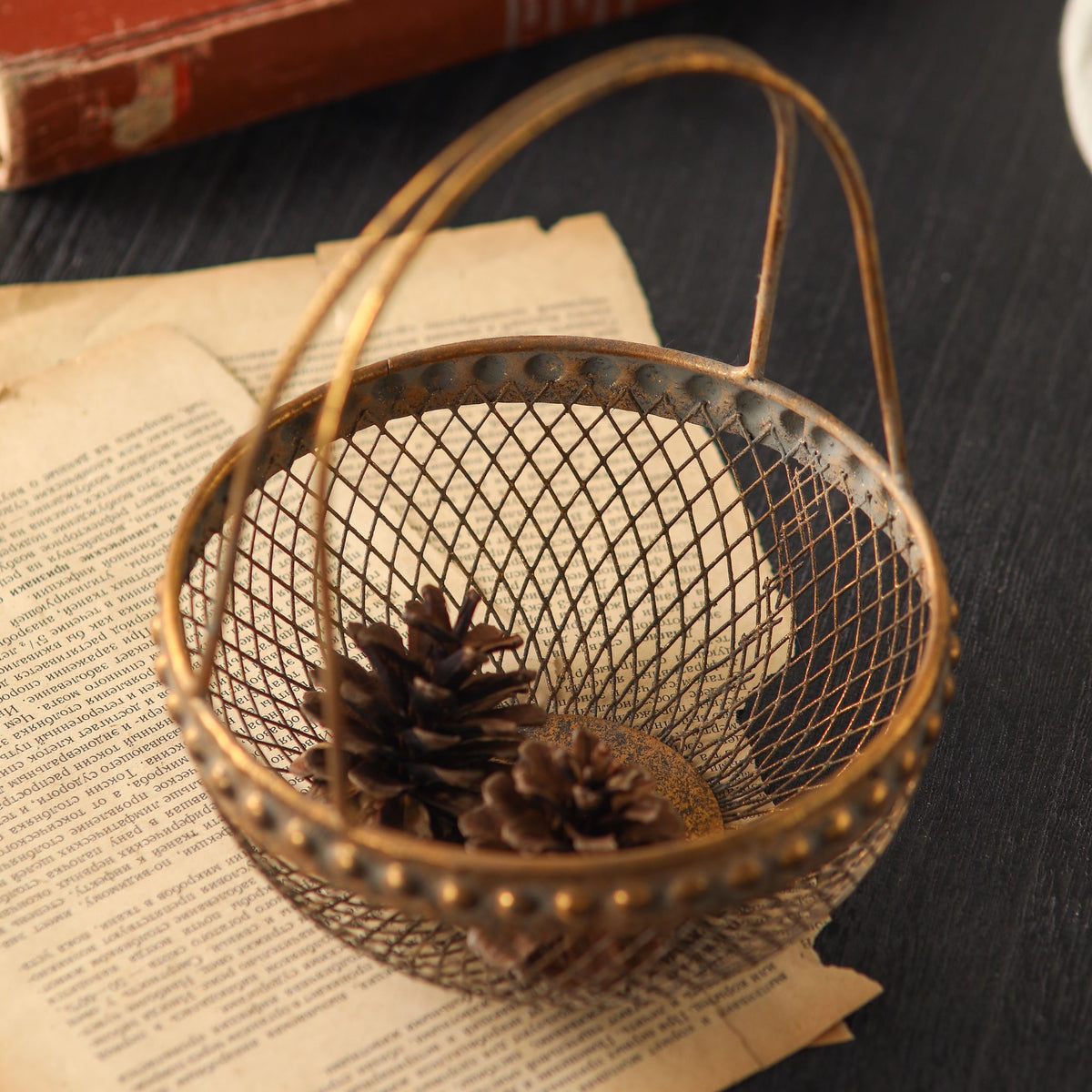 Diane wire basket seen from above holding pine cones, showing the diamond mesh and beaded rim.