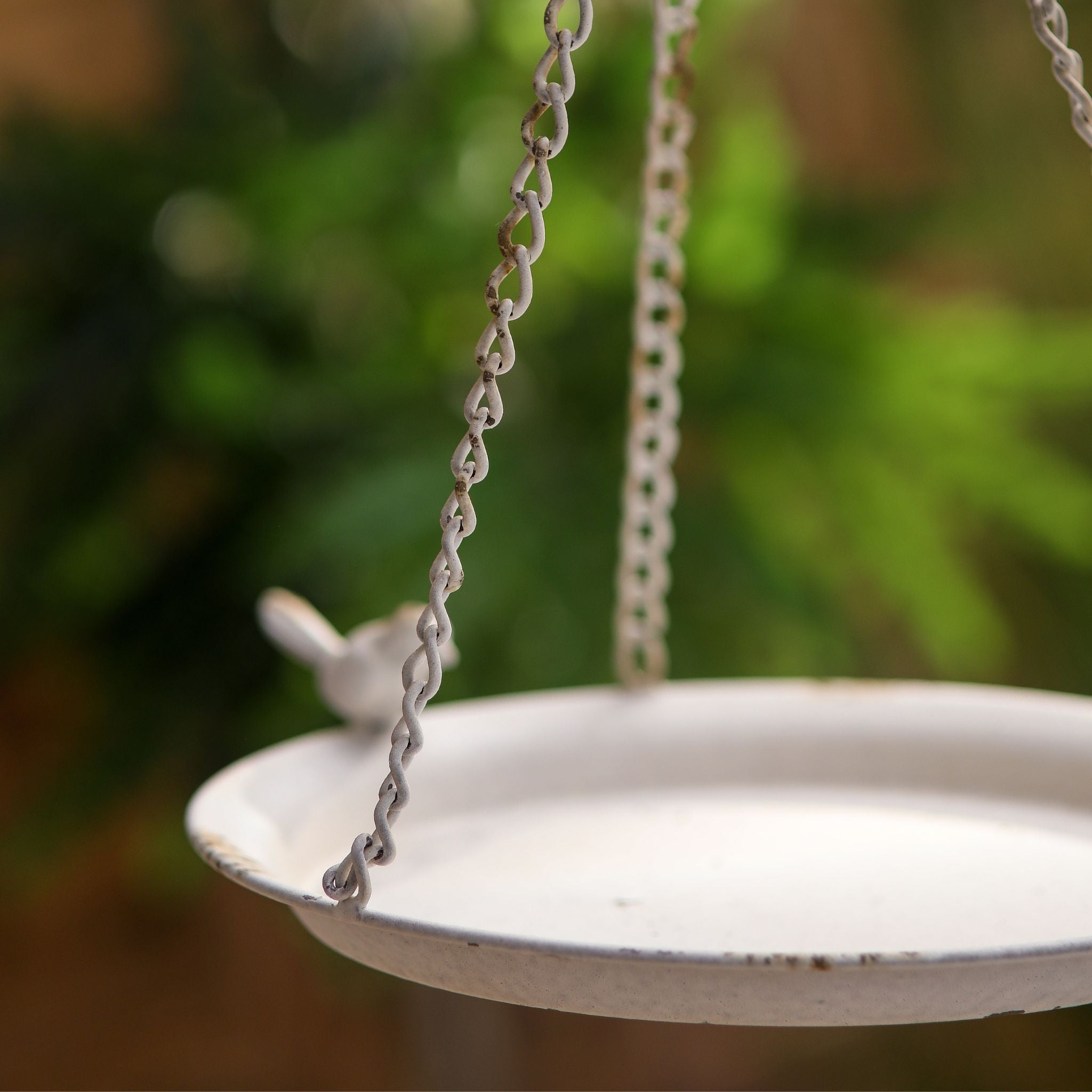 Close-up of the hanging chains and worn distressed white finish on the Fleur bird feeder.